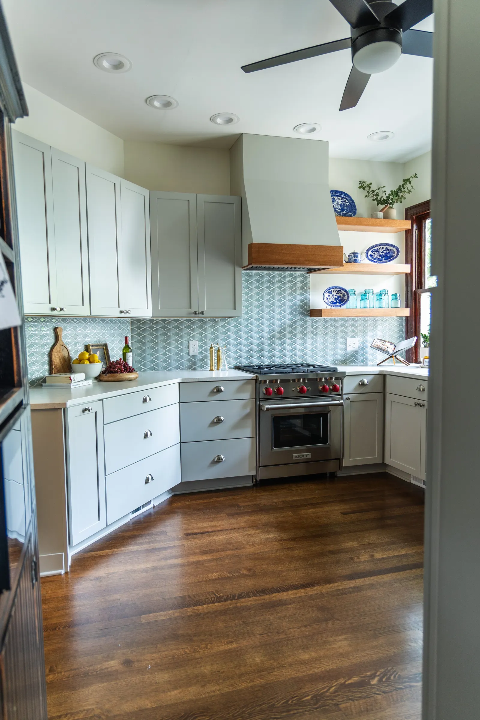 1900 Kitchen Remodel, wood floors, light blue tile backsplash, hardwood floors, open shelving, brushed nickel hardware, wolf oven, stainless steel appliances, custom hood, custom cabinetry, Omaha Nebraska, remodeling and renovations.