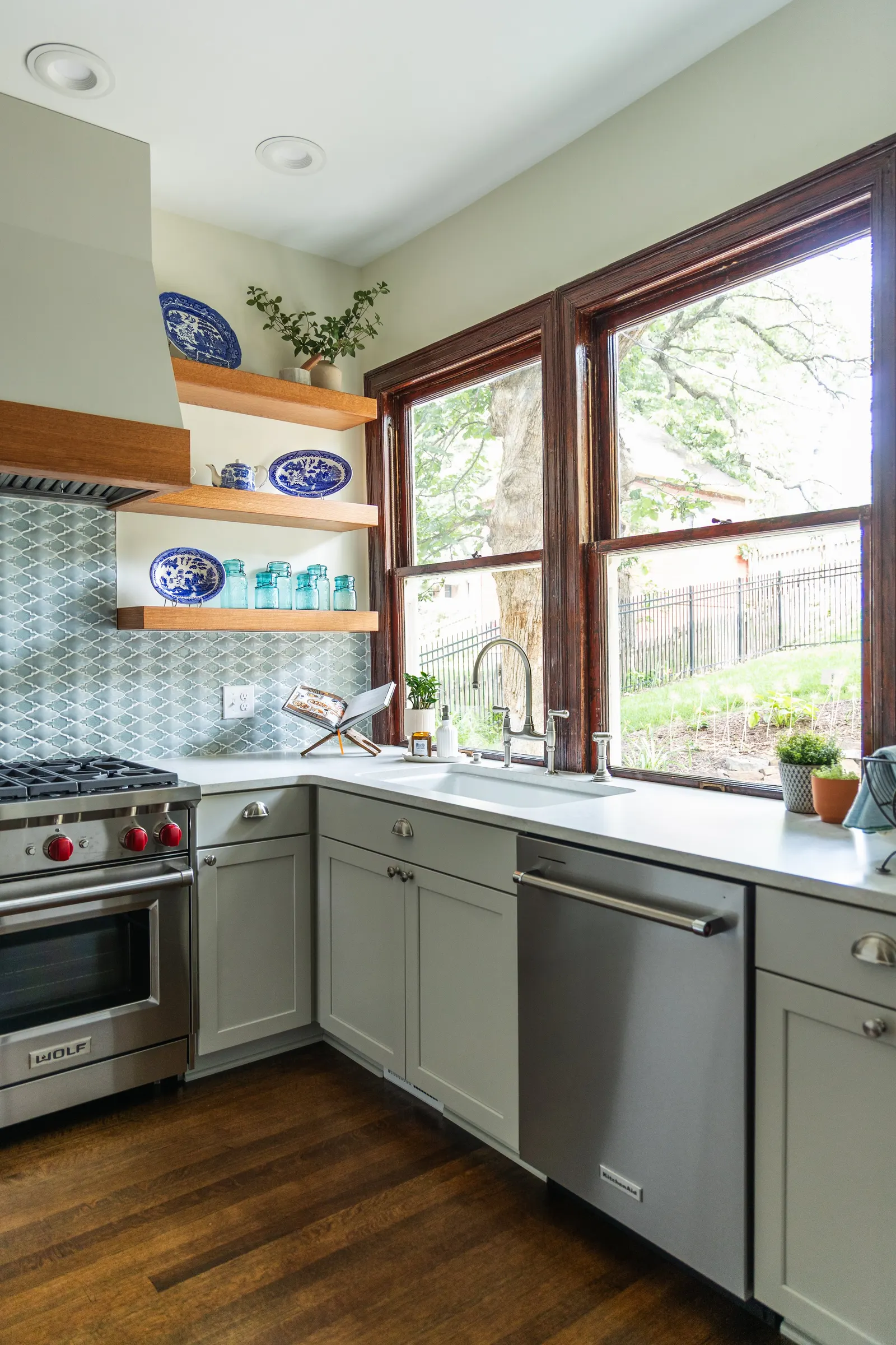 1900 Kitchen Remodel, wood floors, light blue tile backsplash, hardwood floors, open shelving, brushed nickel hardware, wolf oven, stainless steel appliances, custom hood, custom cabinetry, Omaha Nebraska, remodeling and renovations.
