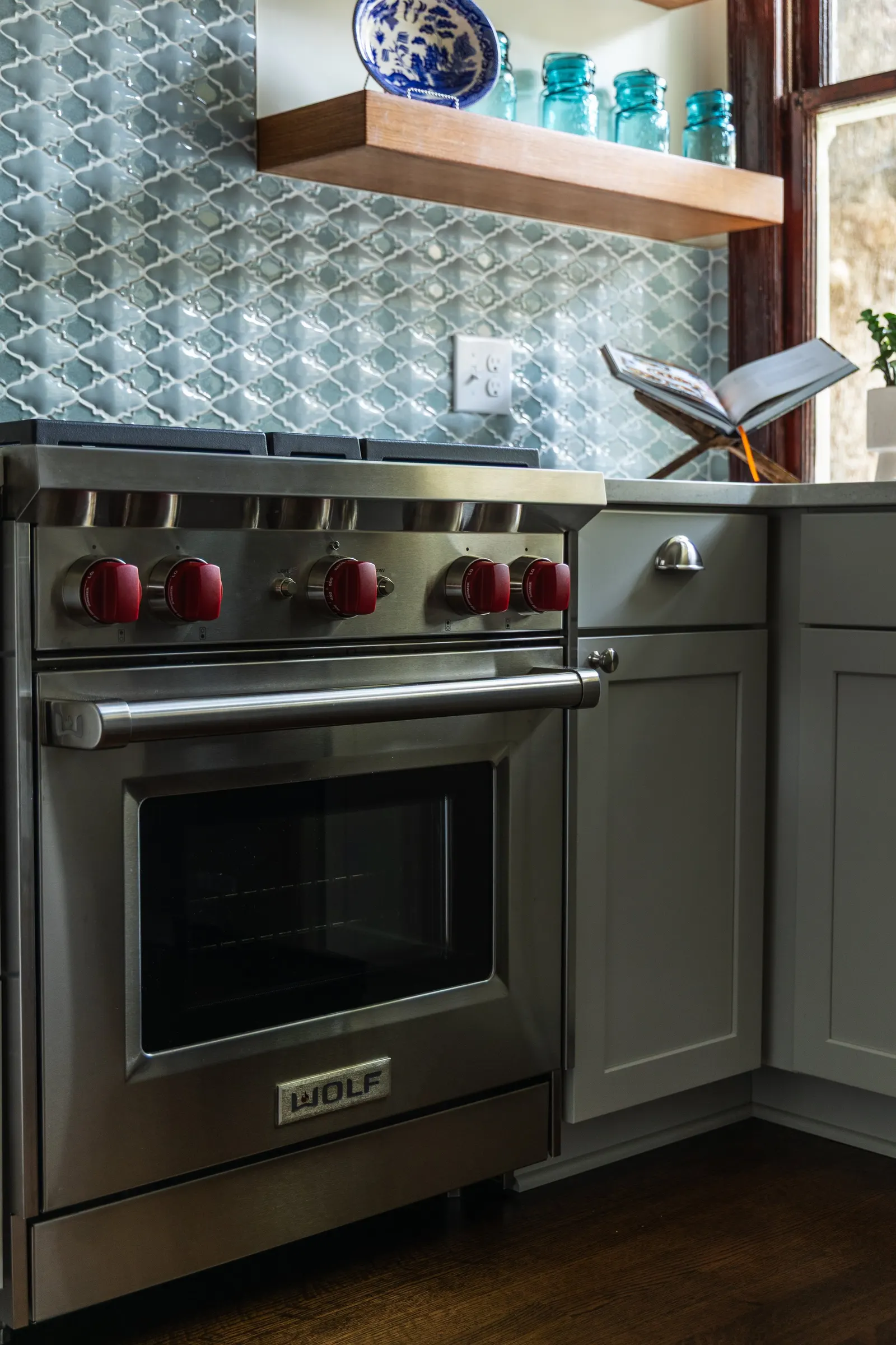 1900 Kitchen Remodel, wood floors, light blue tile backsplash, hardwood floors, open shelving, brushed nickel hardware, wolf oven, stainless steel appliances, custom hood, custom cabinetry, Omaha Nebraska, remodeling and renovations.