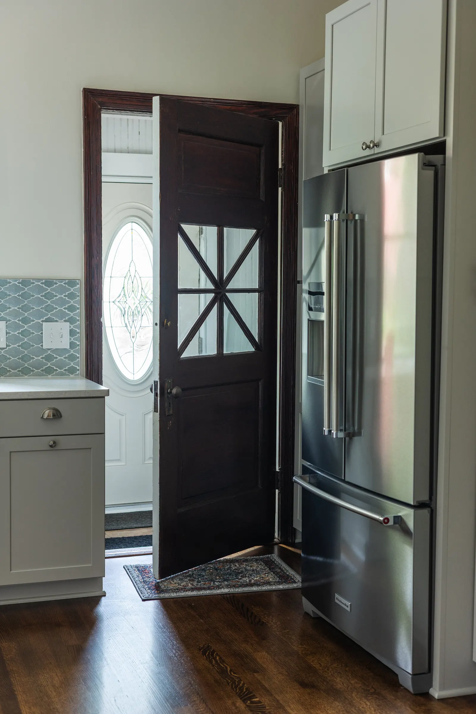 1900 Kitchen Remodel, wood floors, light blue tile backsplash, hardwood floors, open shelving, brushed nickel hardware, wolf oven, stainless steel appliances, custom hood, custom cabinetry, Omaha Nebraska, remodeling and renovations.