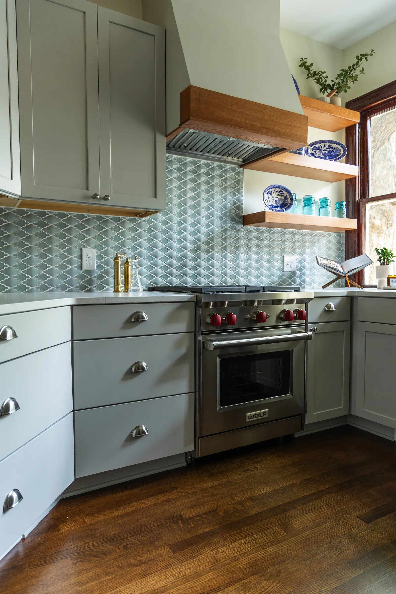 1900 Kitchen Remodel, wood floors, light blue tile backsplash, hardwood floors, open shelving, brushed nickel hardware, wolf oven, stainless steel appliances, custom hood, custom cabinetry, Omaha Nebraska, remodeling and renovations.