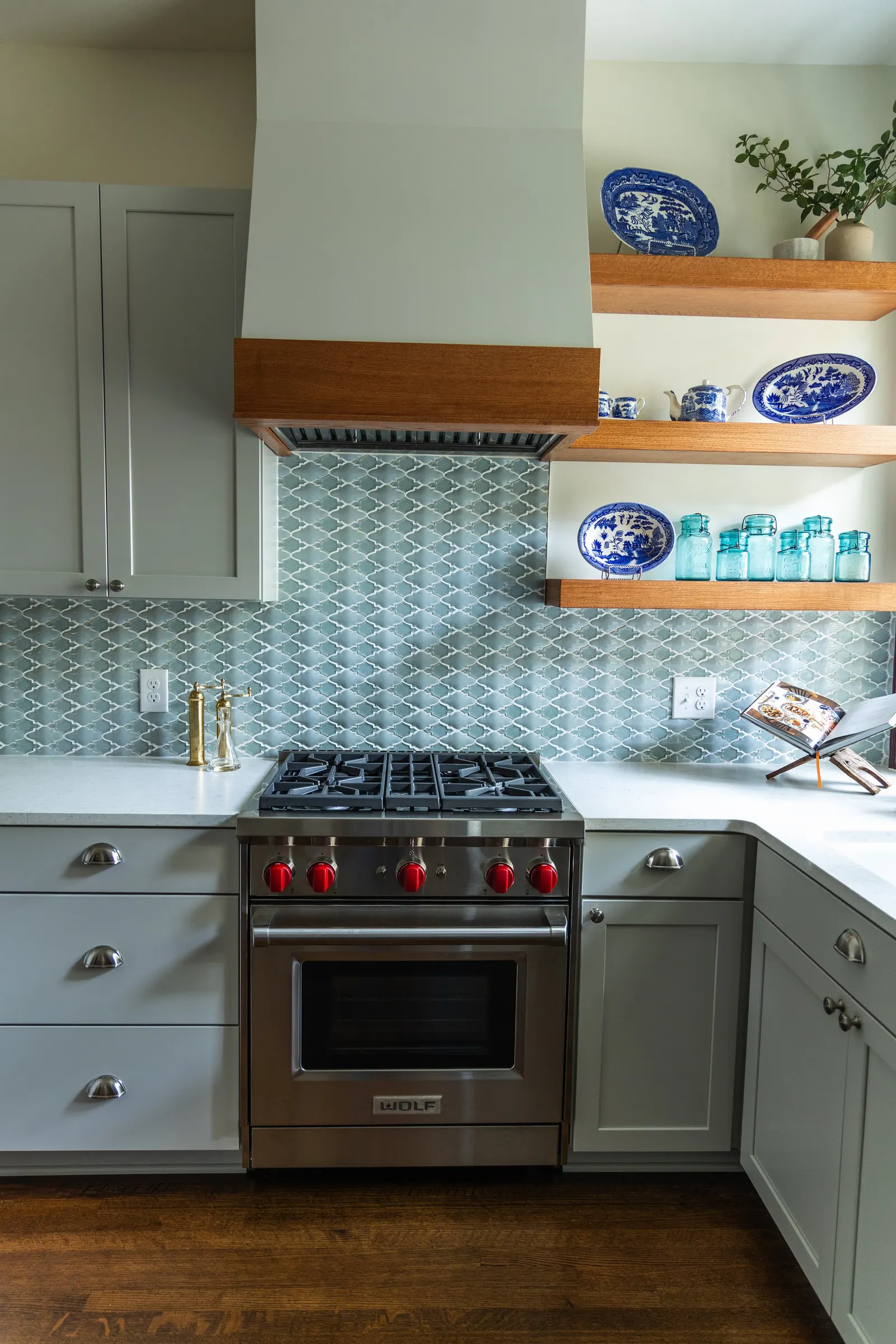 1900 Kitchen Remodel, wood floors, light blue tile backsplash, hardwood floors, open shelving, brushed nickel hardware, wolf oven, stainless steel appliances, custom hood, custom cabinetry, Omaha Nebraska, remodeling and renovations.