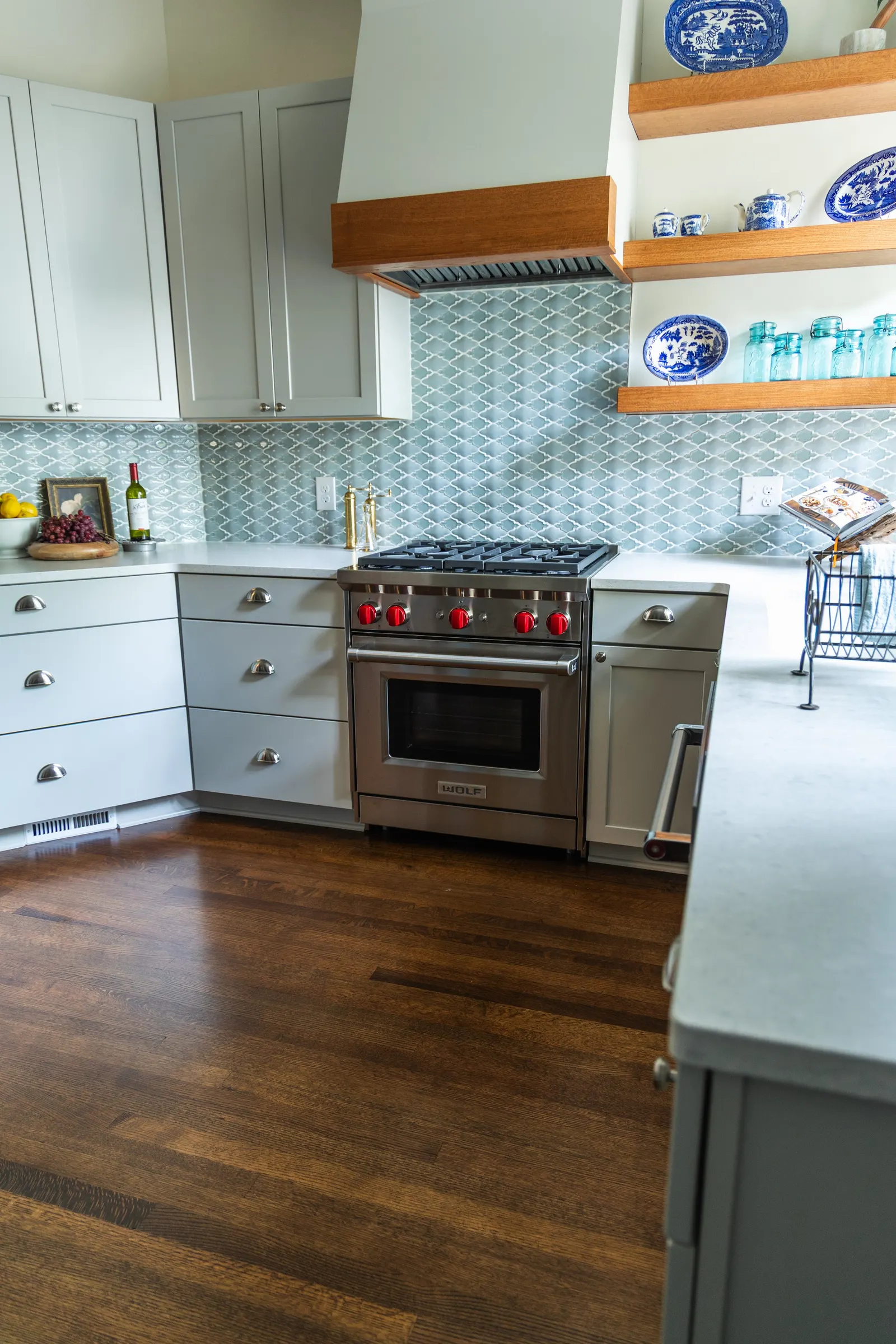 1900 Kitchen Remodel, wood floors, light blue tile backsplash, hardwood floors, open shelving, brushed nickel hardware, wolf oven, stainless steel appliances, custom hood, custom cabinetry, Omaha Nebraska, remodeling and renovations.
