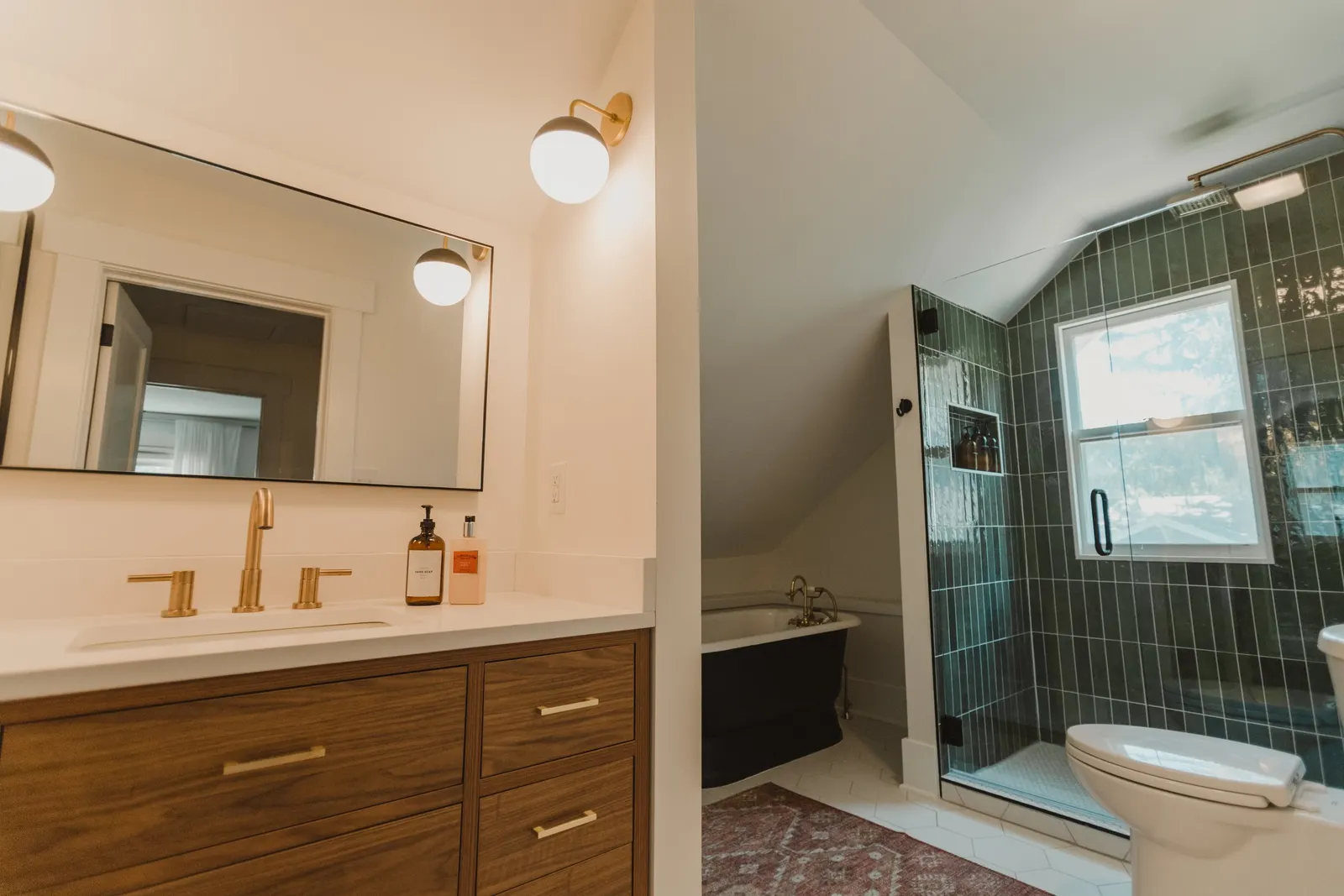 1920 Bathroom Remodel, custom wood vanity, brushed gold faucet, brushed gold sconces, modern design, mixed metal finishes, bathtub, green subway tile, white hexagon floor tile, Lincoln Nebraska, professional contractors, remodeling and renovations.
