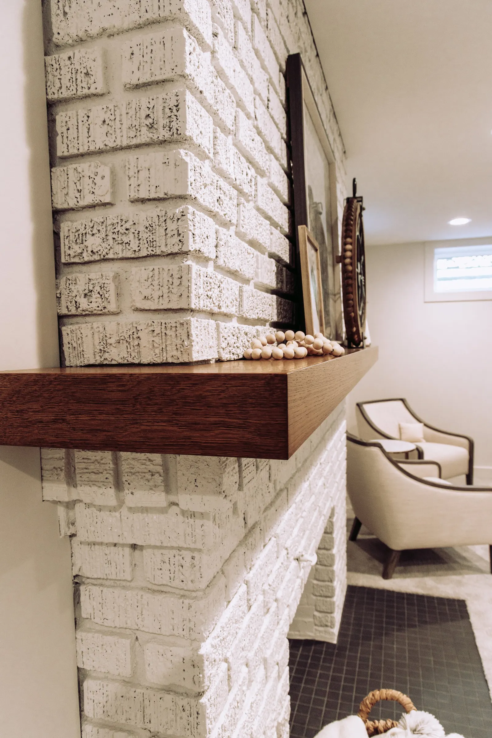 1922 Basement Remodel, carpet, brick fireplace, custom wood mantel, white cabinets, matte black hardware, matte black sconces, open shelves, floating wood shelves, custom woodworking, Lincoln Nebraska, professional contractors, craftsmanship.