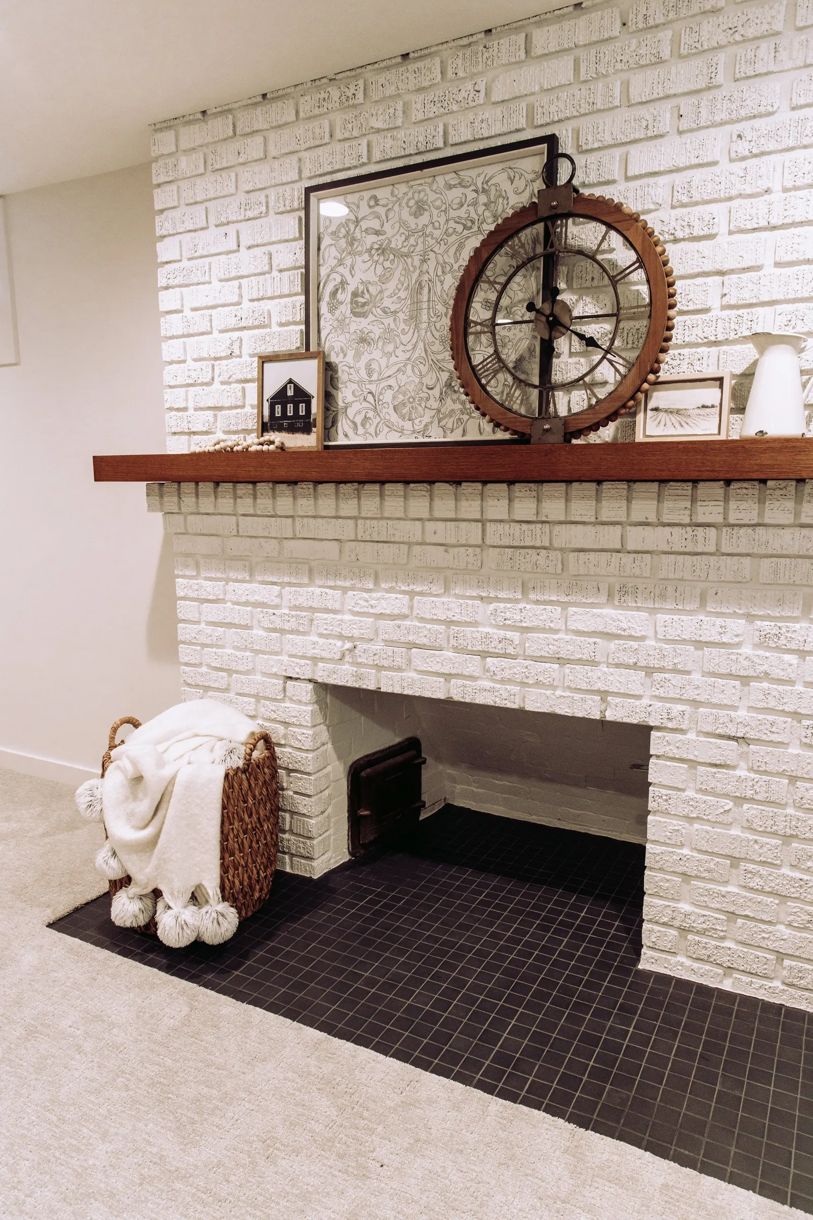1922 Basement Remodel, carpet, brick fireplace, custom wood mantel, white cabinets, matte black hardware, matte black sconces, open shelves, floating wood shelves, custom woodworking, Lincoln Nebraska, professional contractors, craftsmanship.