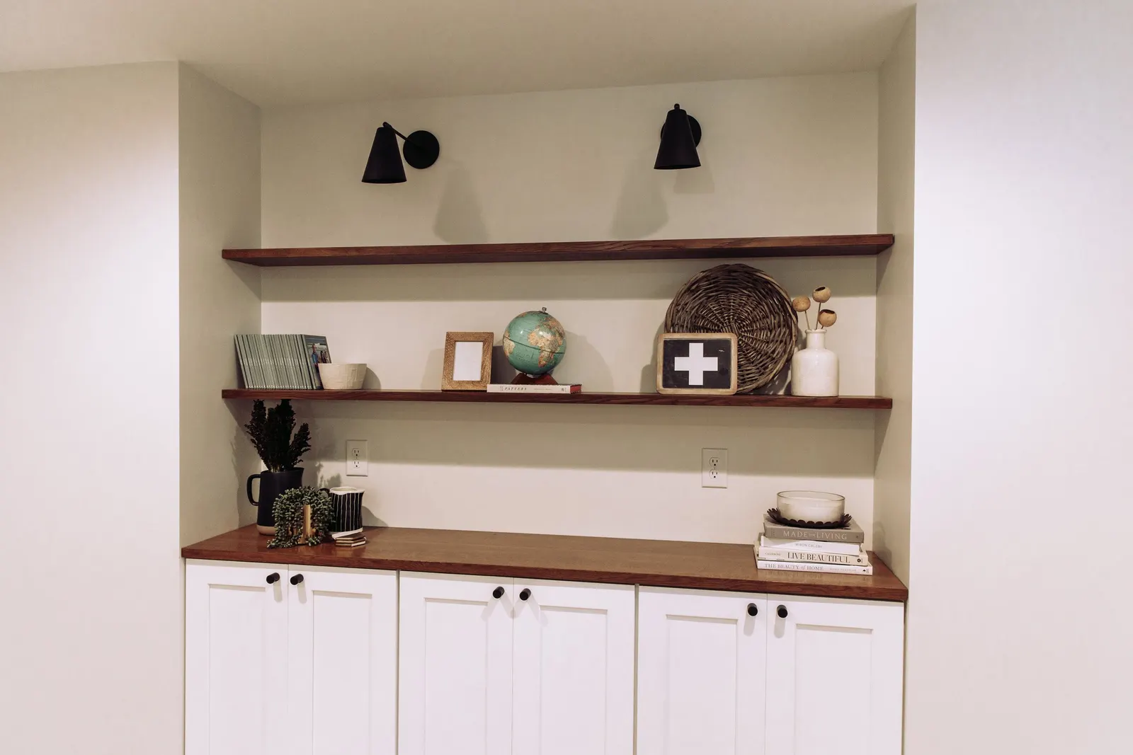 1922 Basement Remodel, carpet, brick fireplace, custom wood mantel, white cabinets, matte black hardware, matte black sconces, open shelves, floating wood shelves, custom woodworking, Lincoln Nebraska, professional contractors, craftsmanship.