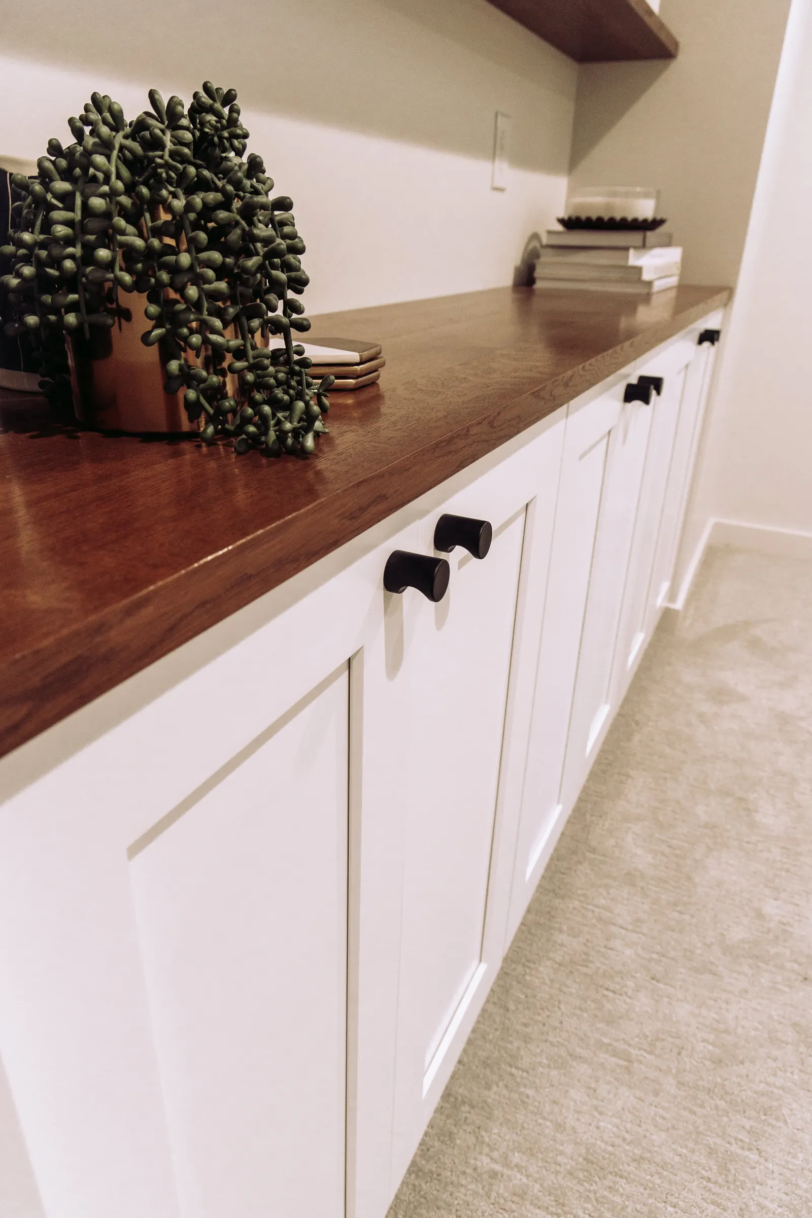 1922 Basement Remodel, carpet, brick fireplace, custom wood mantel, white cabinets, matte black hardware, matte black sconces, open shelves, floating wood shelves, custom woodworking, Lincoln Nebraska, professional contractors, craftsmanship.