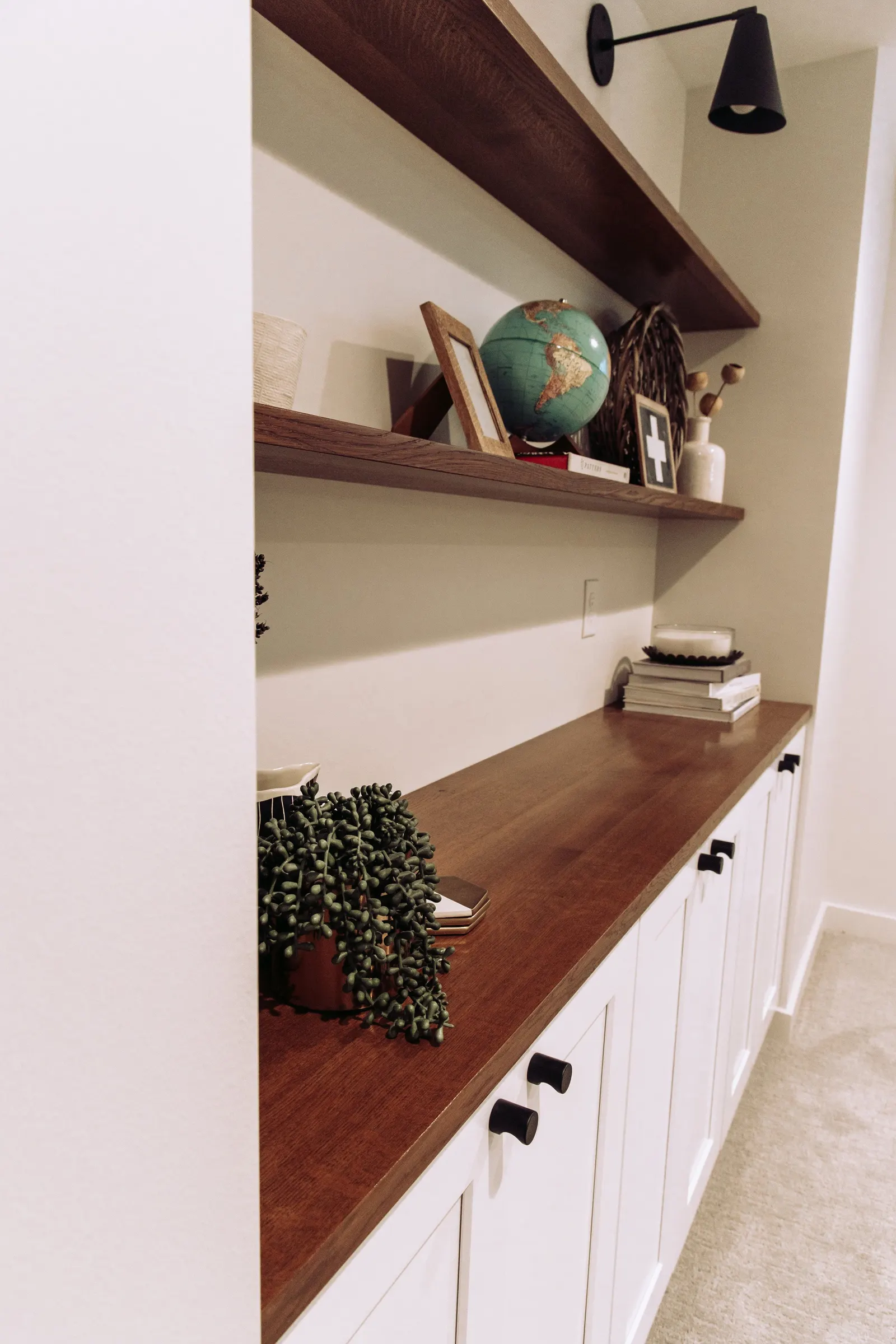 1922 Basement Remodel, carpet, brick fireplace, custom wood mantel, white cabinets, matte black hardware, matte black sconces, open shelves, floating wood shelves, custom woodworking, Lincoln Nebraska, professional contractors, craftsmanship.