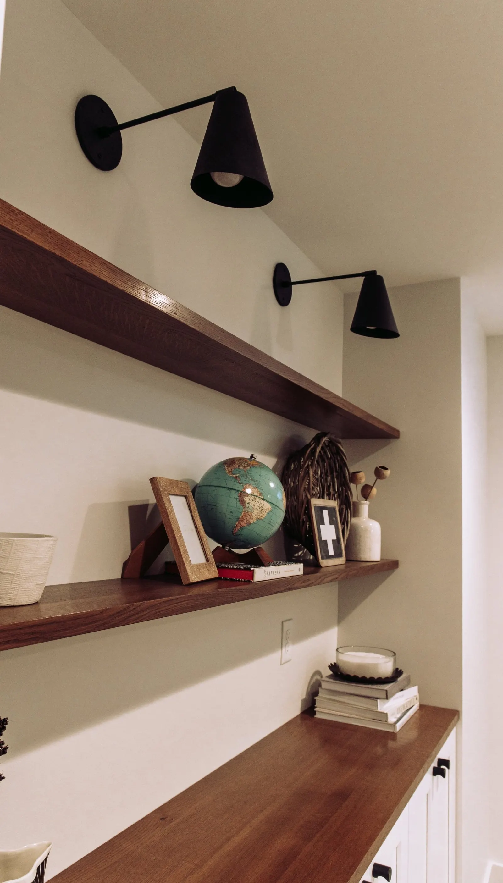 1922 Basement Remodel, carpet, brick fireplace, custom wood mantel, white cabinets, matte black hardware, matte black sconces, open shelves, floating wood shelves, custom woodworking, Lincoln Nebraska, professional contractors, craftsmanship.