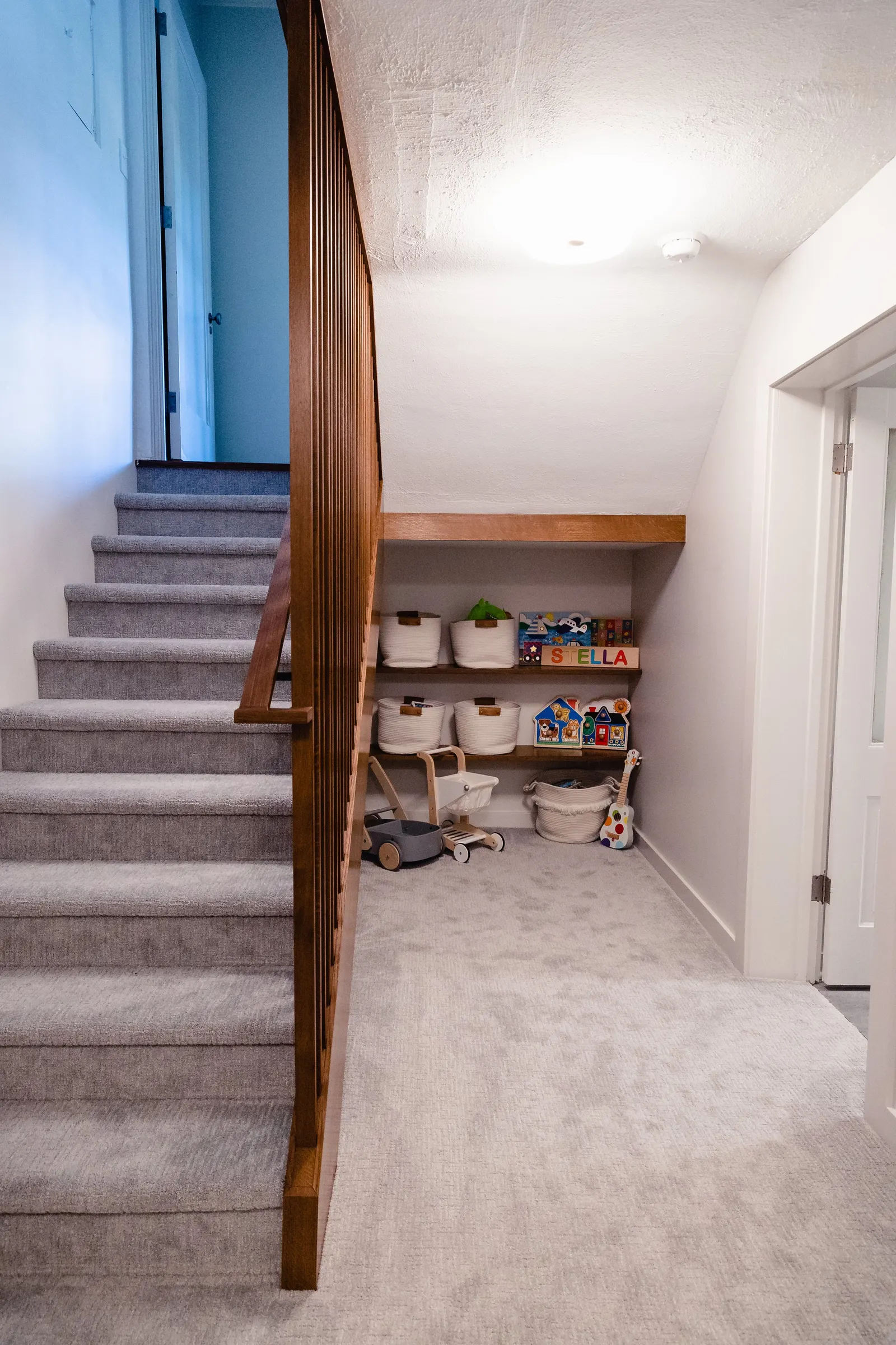 1922 Basement Remodel, carpet, brick fireplace, white cabinets, matte black hardware, open shelves, floating wood shelves, custom woodworking, Lincoln Nebraska, professional contractors, craftsmanship.