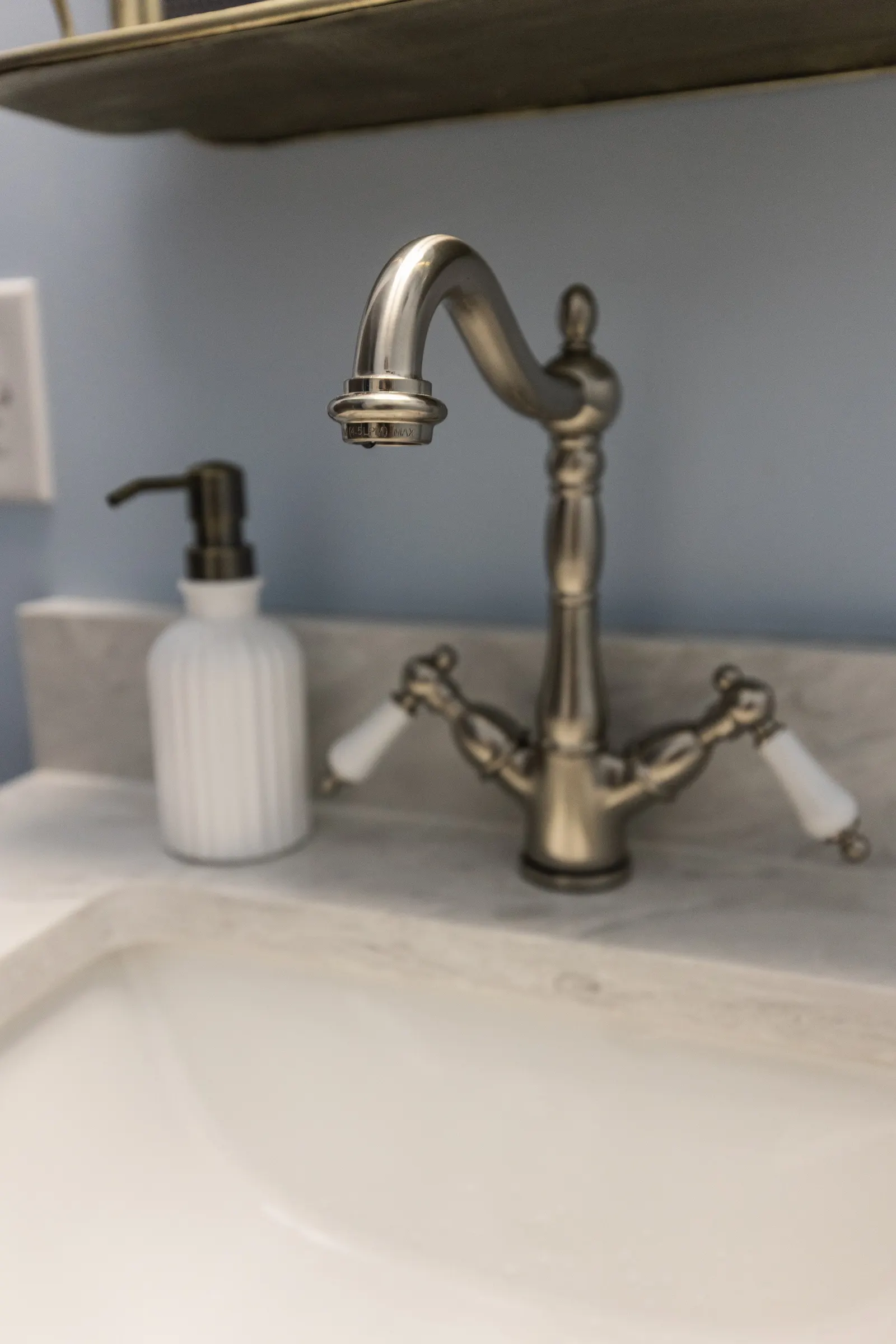 A kitchen sink with a brushed nickel faucet and a soap dispenser on the countertop.