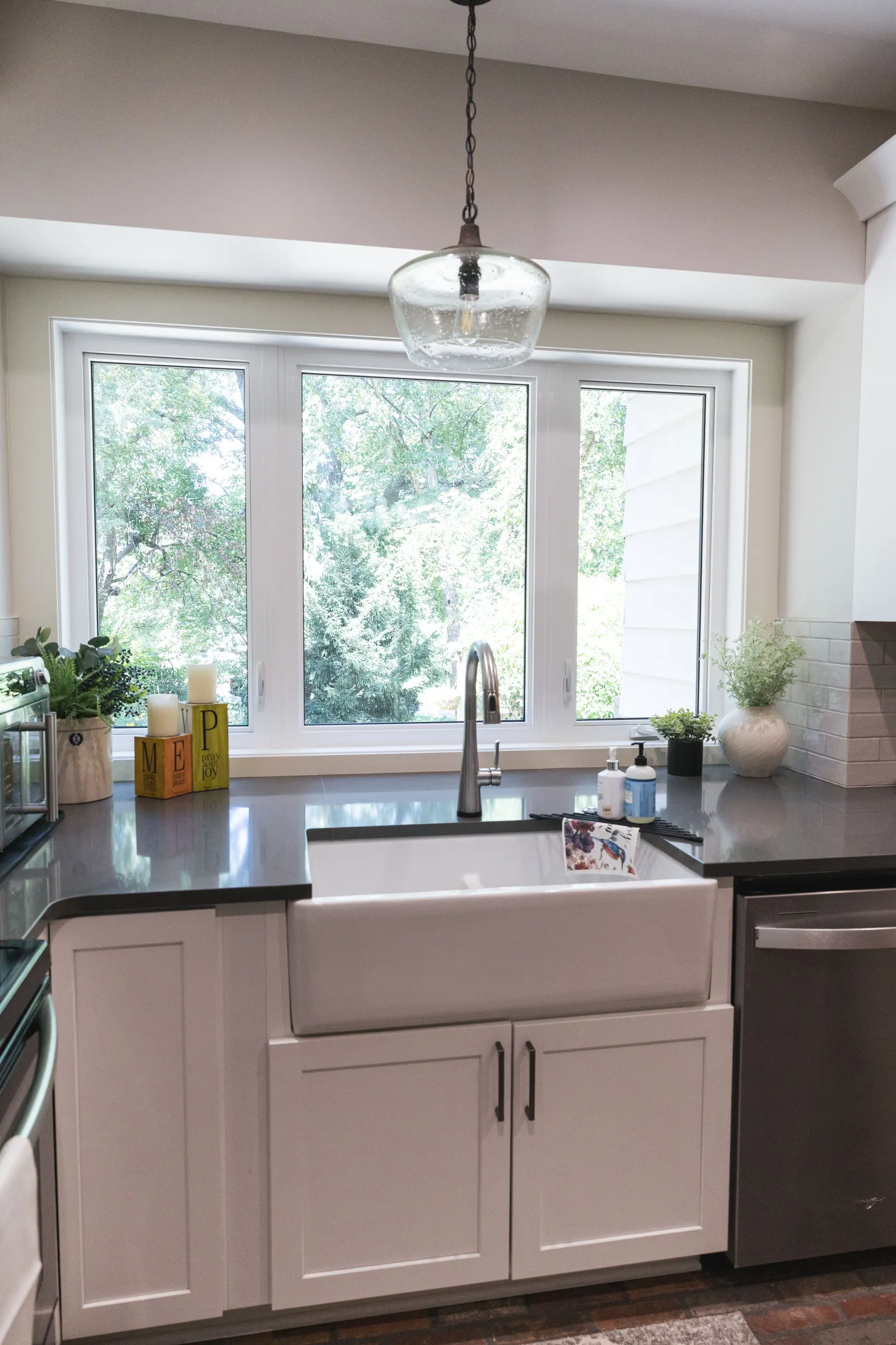 The bay window and fireclay sink under a glass pendant light.