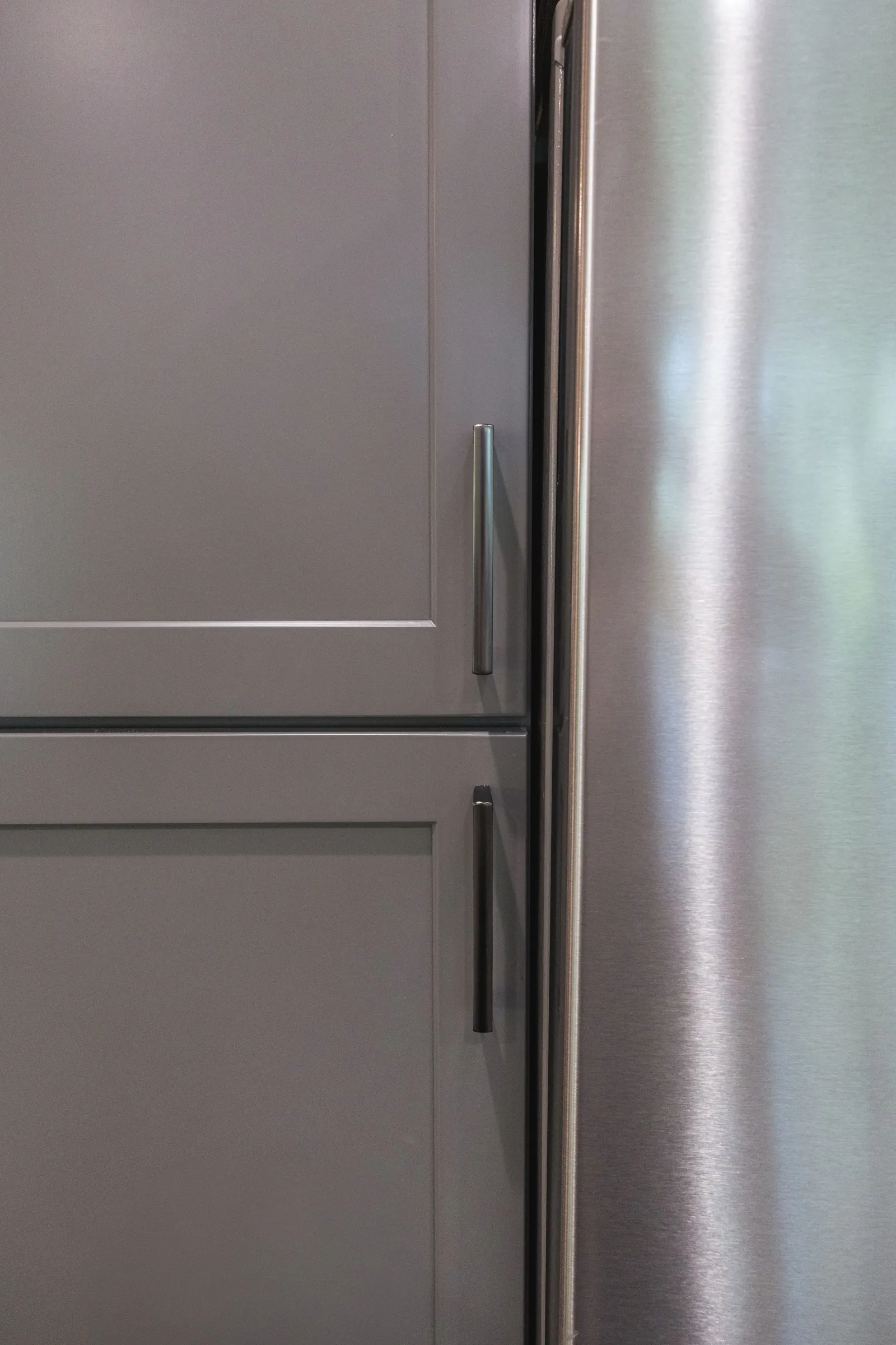 Detail of the gray cabinetry beside the refrigerator.