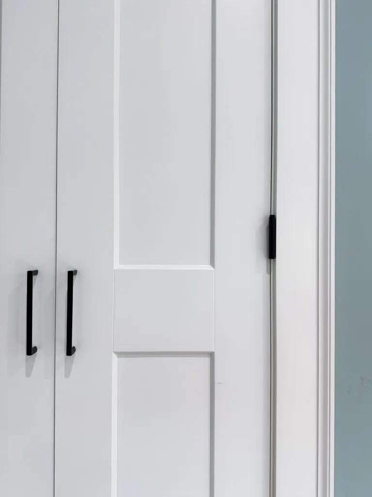 White closet or cabinet with black handles and a sliding door.