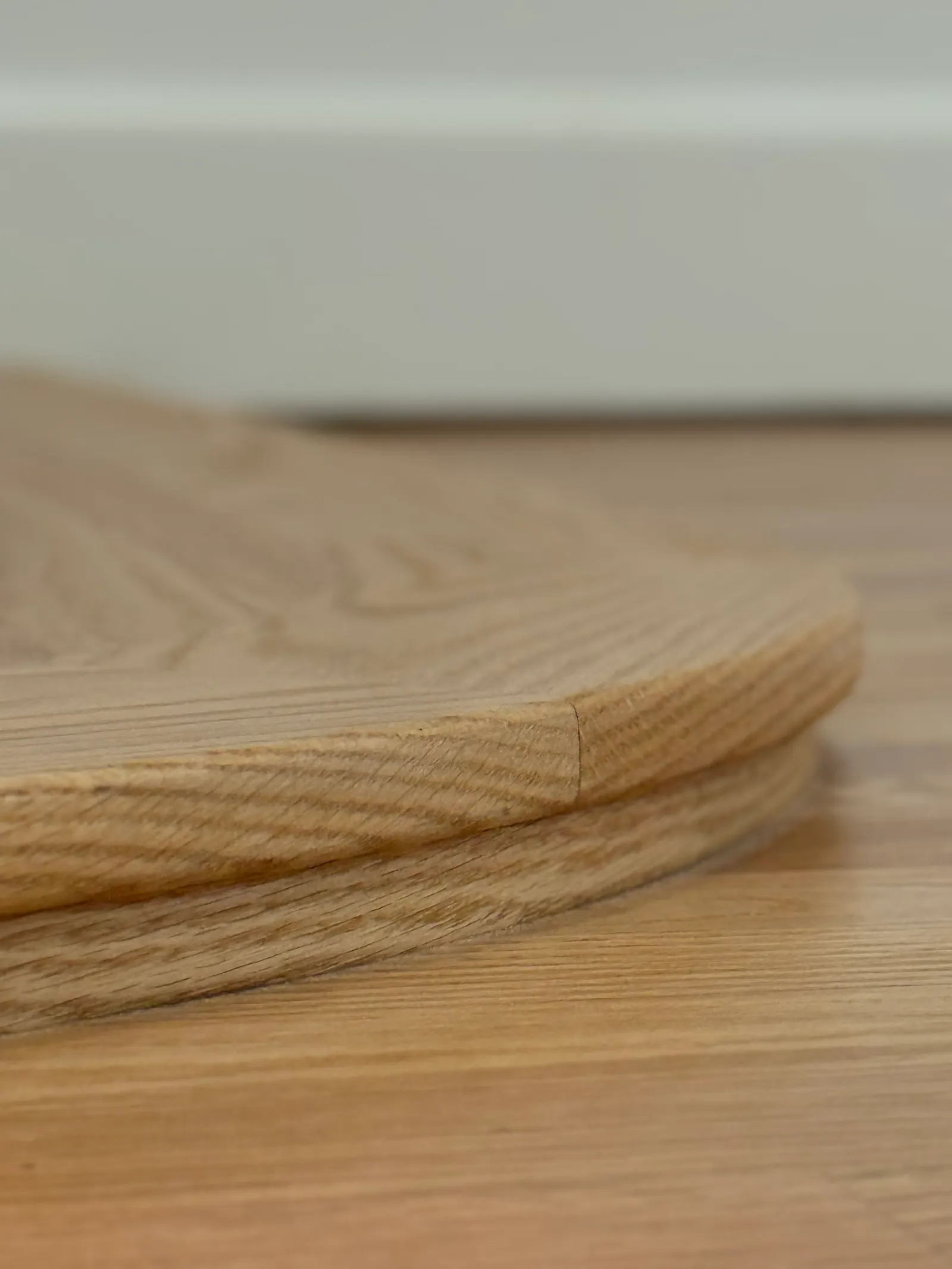 Close-up of a stack of round wooden coasters on a light wooden surface.
