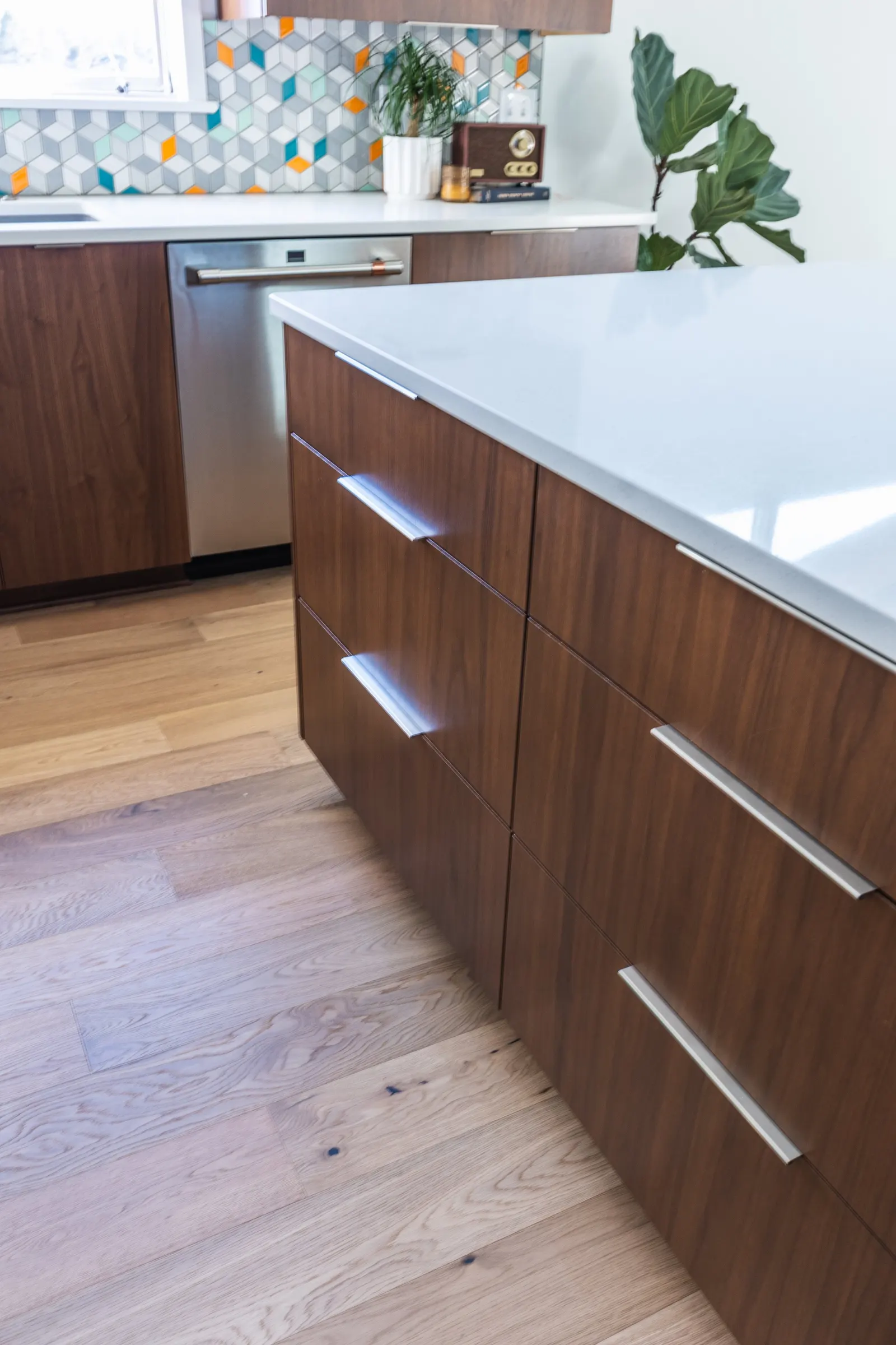 1956 Kitchen Remodel, mid century modern design, mixed metals, wood cabinets, colorful tile backsplash, close-up of a modern kitchen with wood cabinets, a white countertop, a colorful hexagonal tile backsplash, and a light wooden floor.