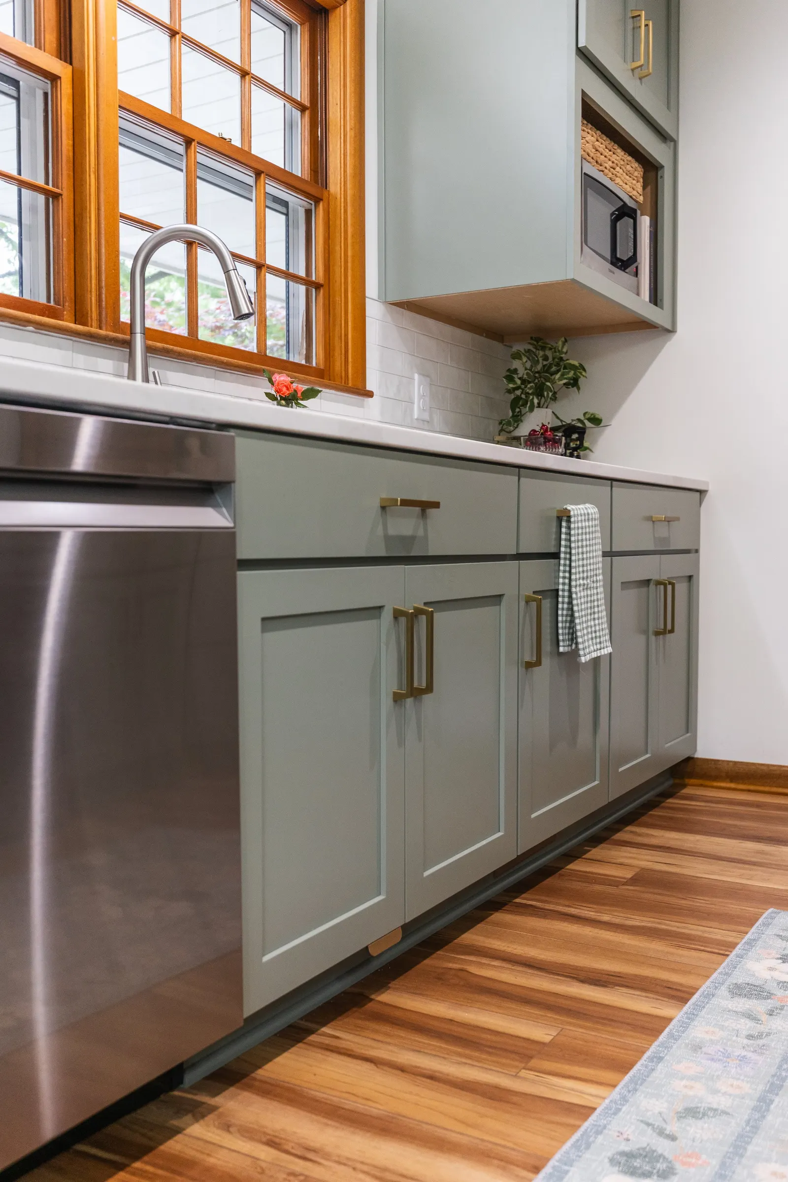 1958 Kitchen Remodel, mid century design, wood floors, stainless steel appliances, sage green cabinets, brushed gold hardware, white quartz countertop, modern light fixtures, Lincoln Nebraska, professional contractors, remodeling and renovations.