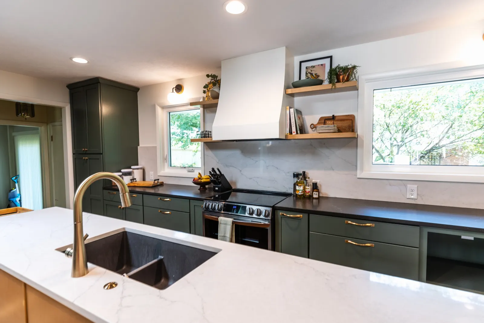 1962 Kitchen Remodel, dark green cabinets, white quartz island, wooden floors, brass hardware, wood cabinets, custom hood, floating shelves, dark countertops, open shelving