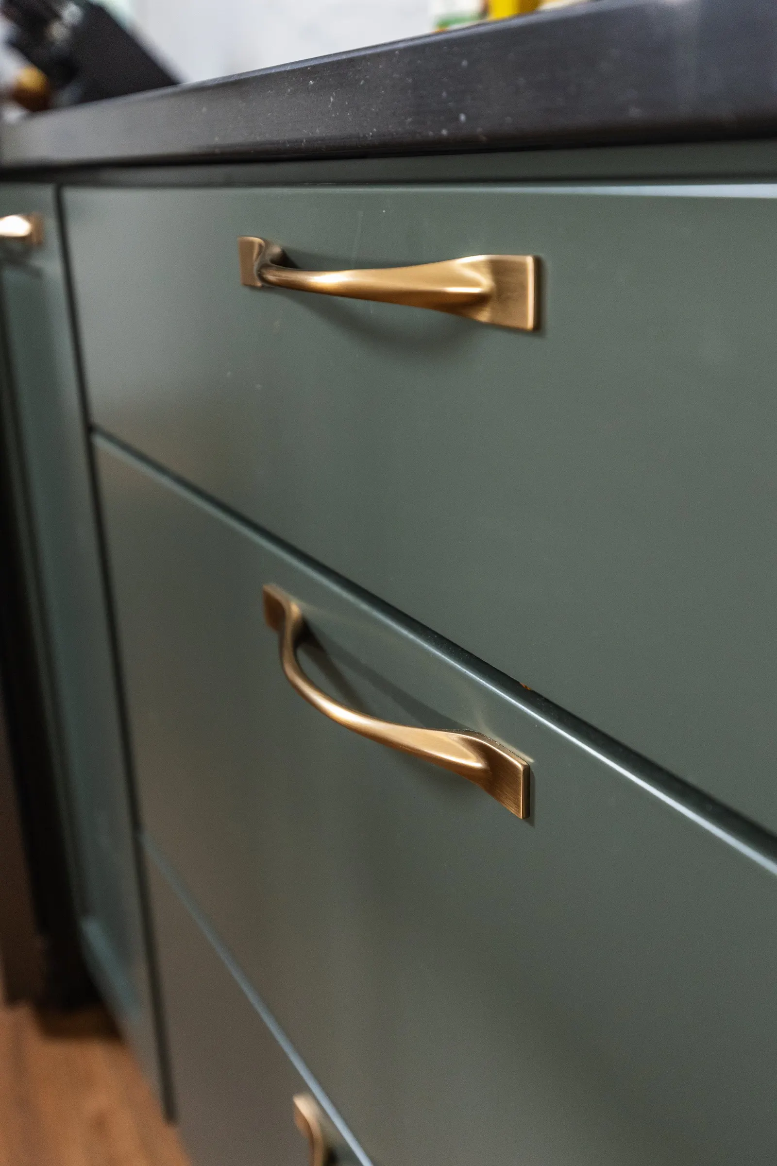 1962 Kitchen Remodel, dark green cabinets, white quartz island, wooden floors, brass hardware, wood cabinets, custom hood, floating shelves, dark countertops, open shelving, large windows, craftsmanship, custom cabinets.