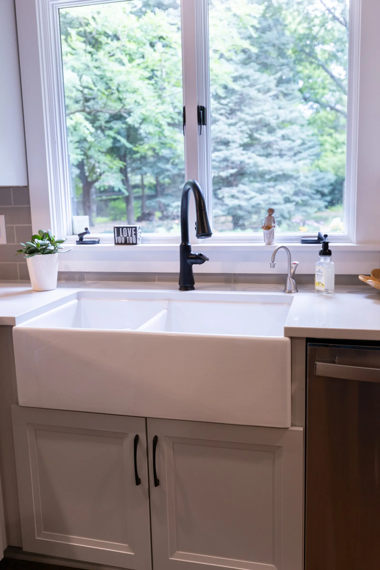 1974 Whole Home Remodel, kitchen remodel, wood floors, quartz countertop, craftsmanship, farmhouse style, custom hood, white cabinets, matte black hardware, farmhouse sink, pendant lights, large island, dual tone kitchen, large windows, patio doors.