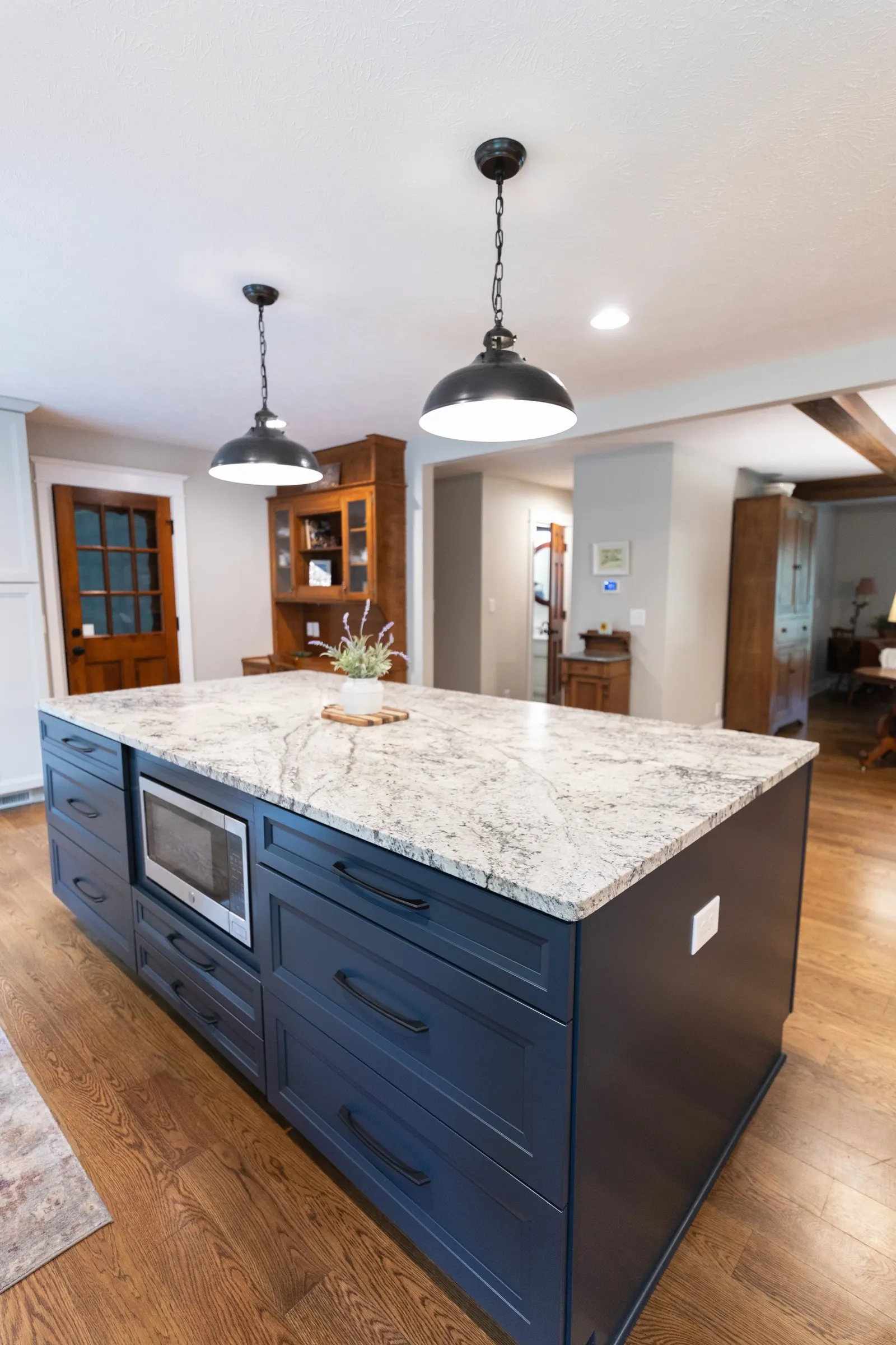 1974 Whole Home Remodel, kitchen remodel, wood floors, quartz countertop, craftsmanship, farmhouse style, custom hood, white cabinets, matte black hardware, farmhouse sink, pendant lights, large island, dual tone kitchen, large windows, patio doors.