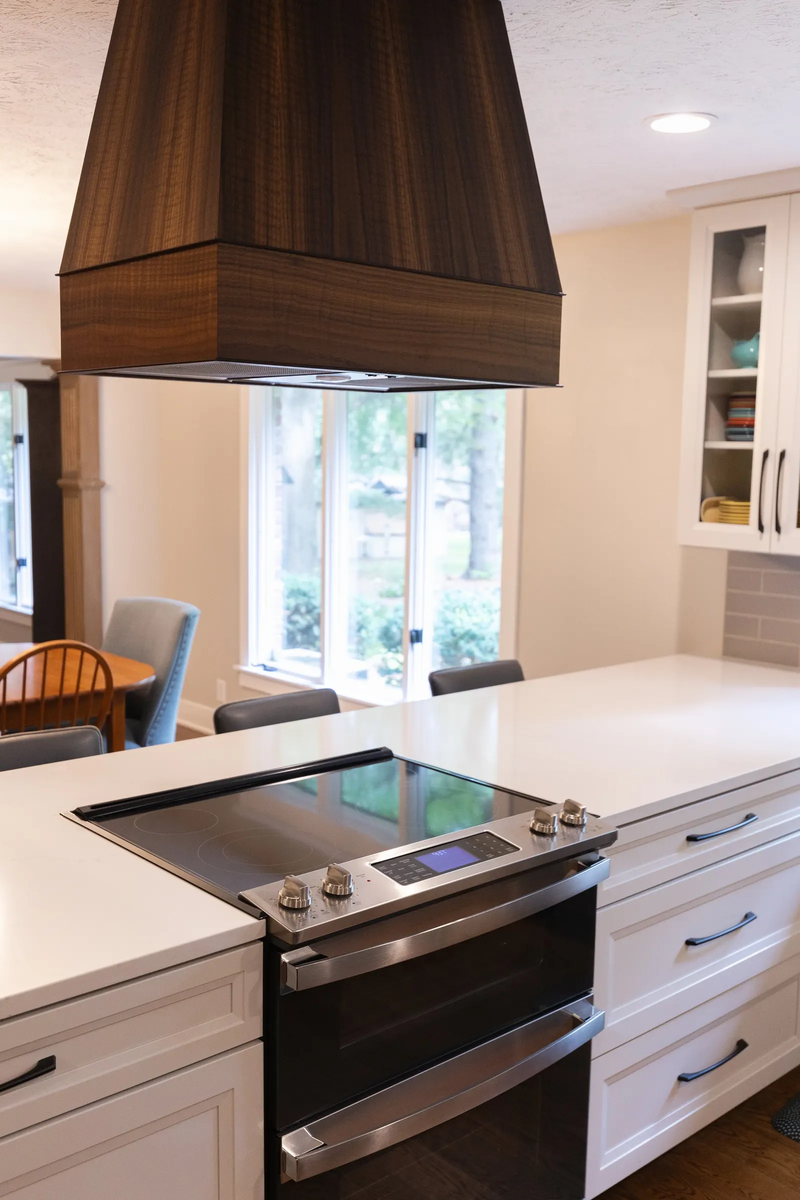 1974 Whole Home Remodel, kitchen remodel, wood floors, quartz countertop, craftsmanship, farmhouse style, custom hood, white cabinets, matte black hardware, farmhouse sink, pendant lights, large island, dual tone kitchen, large windows, patio doors.