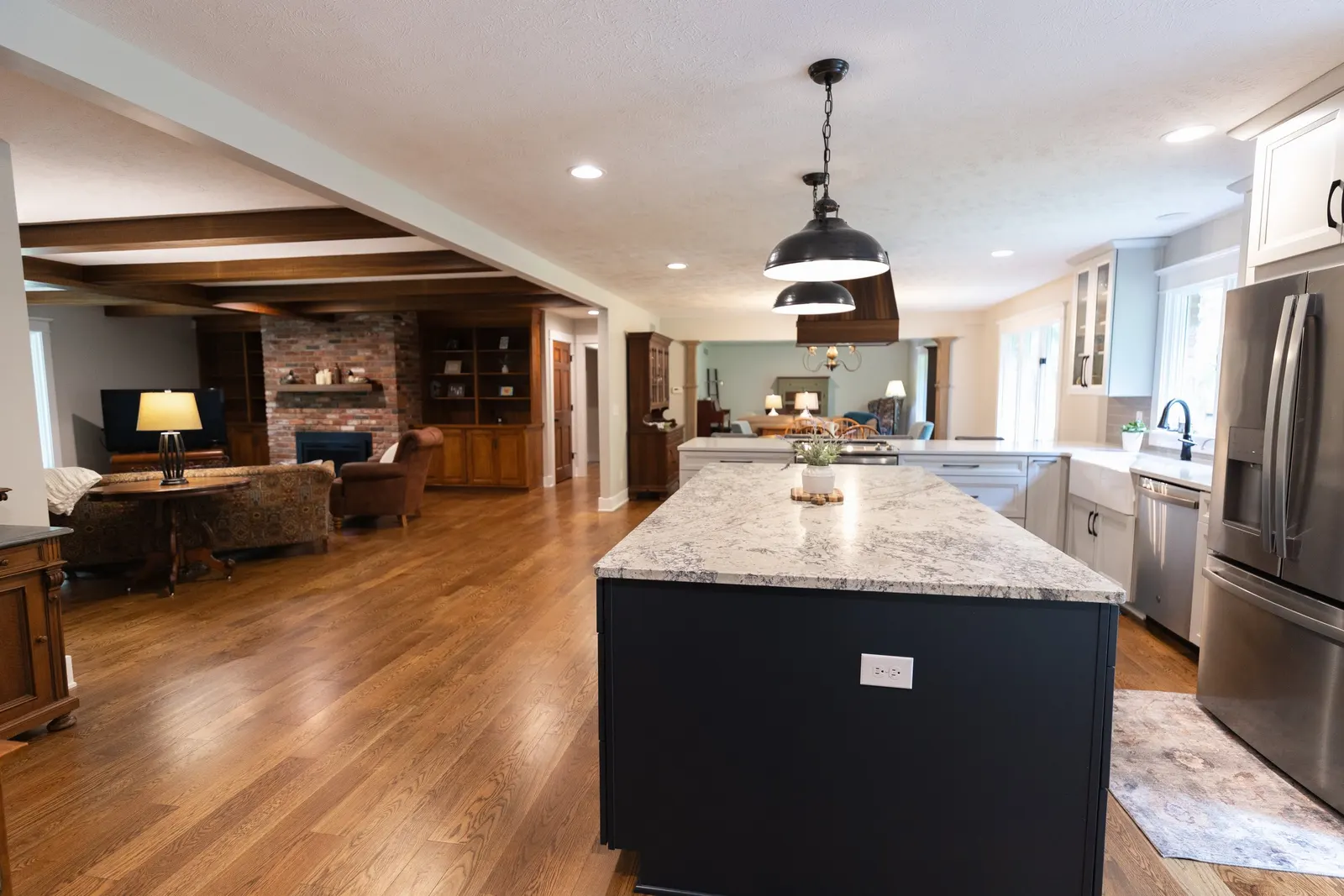 1974 Whole Home Remodel, kitchen remodel, wood floors, quartz countertop, craftsmanship, farmhouse style, custom hood, white cabinets, matte black hardware, farmhouse sink, pendant lights, large island, dual tone kitchen, large windows, patio doors.