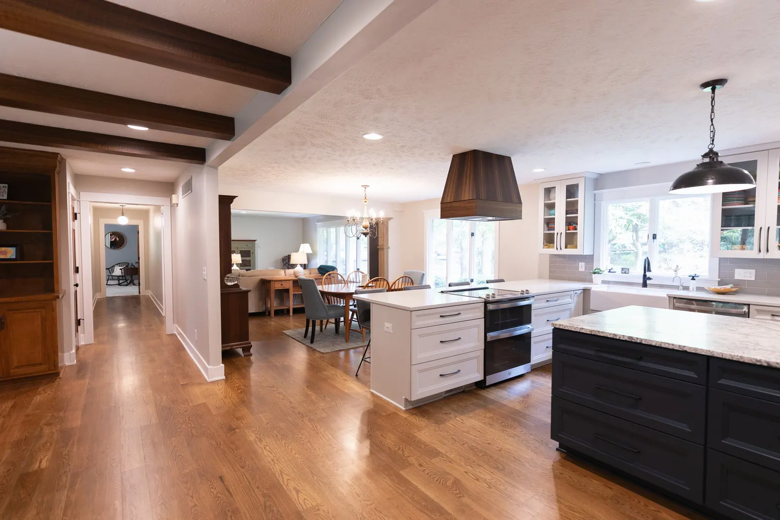 1974 Whole Home Remodel, kitchen remodel, wood floors, quartz countertop, craftsmanship, farmhouse style, custom hood, white cabinets, matte black hardware, farmhouse sink, pendant lights, large island, dual tone kitchen, large windows, patio doors.