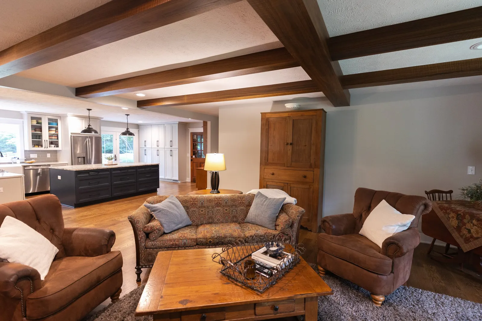 1974 Living Room Remodel, whole home remodel, wood floors, craftsmanship, farmhouse style, custom hood, white cabinets, matte black hardware, farmhouse sink, pendant lights, large island, dual tone kitchen, large windows, custom wood beams.