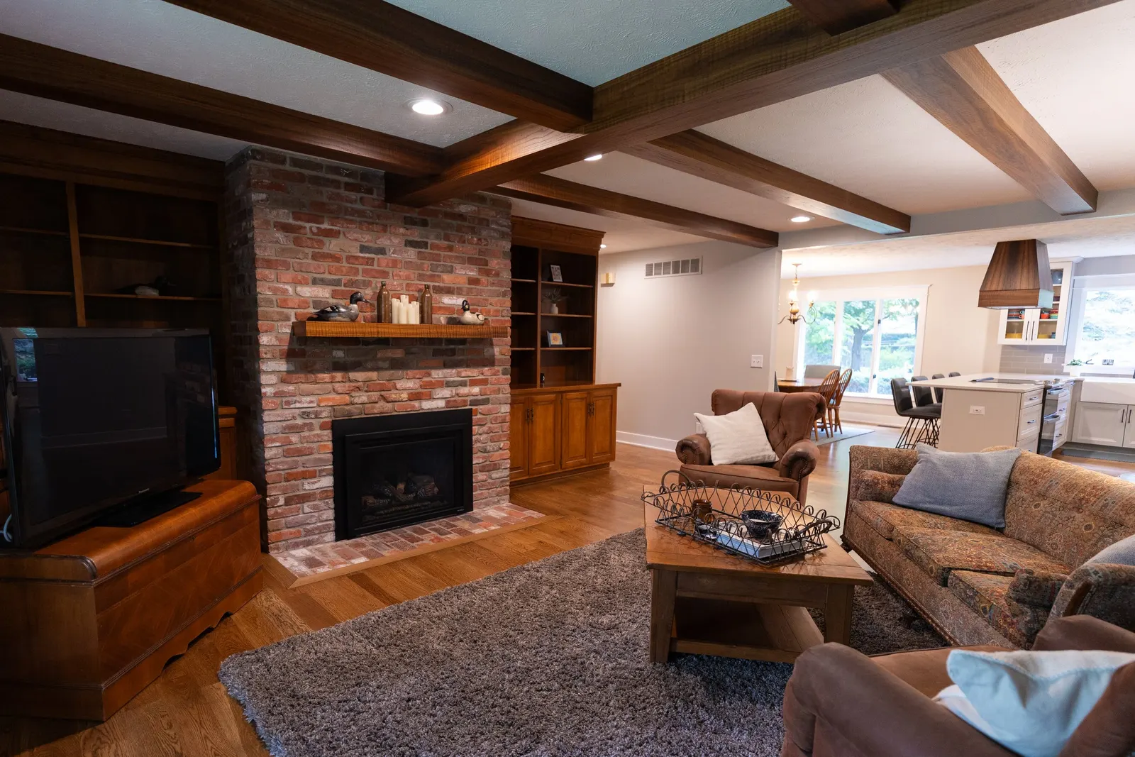 1974 Living Room Remodel, whole home remodel, wood floors, craftsmanship, farmhouse style, large windows, custom wood beams, brick fireplace, wood built-ins, can lighting, dark wood, craftsmanship, wood mantel.