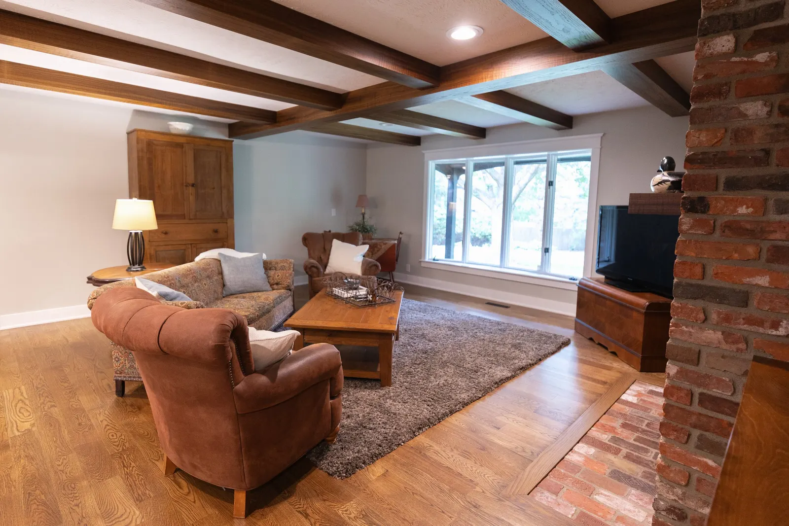 1974 Living Room Remodel, whole home remodel, wood floors, craftsmanship, farmhouse style, large windows, custom wood beams, brick fireplace, wood built-ins, can lighting, dark wood, craftsmanship, wood mantel.