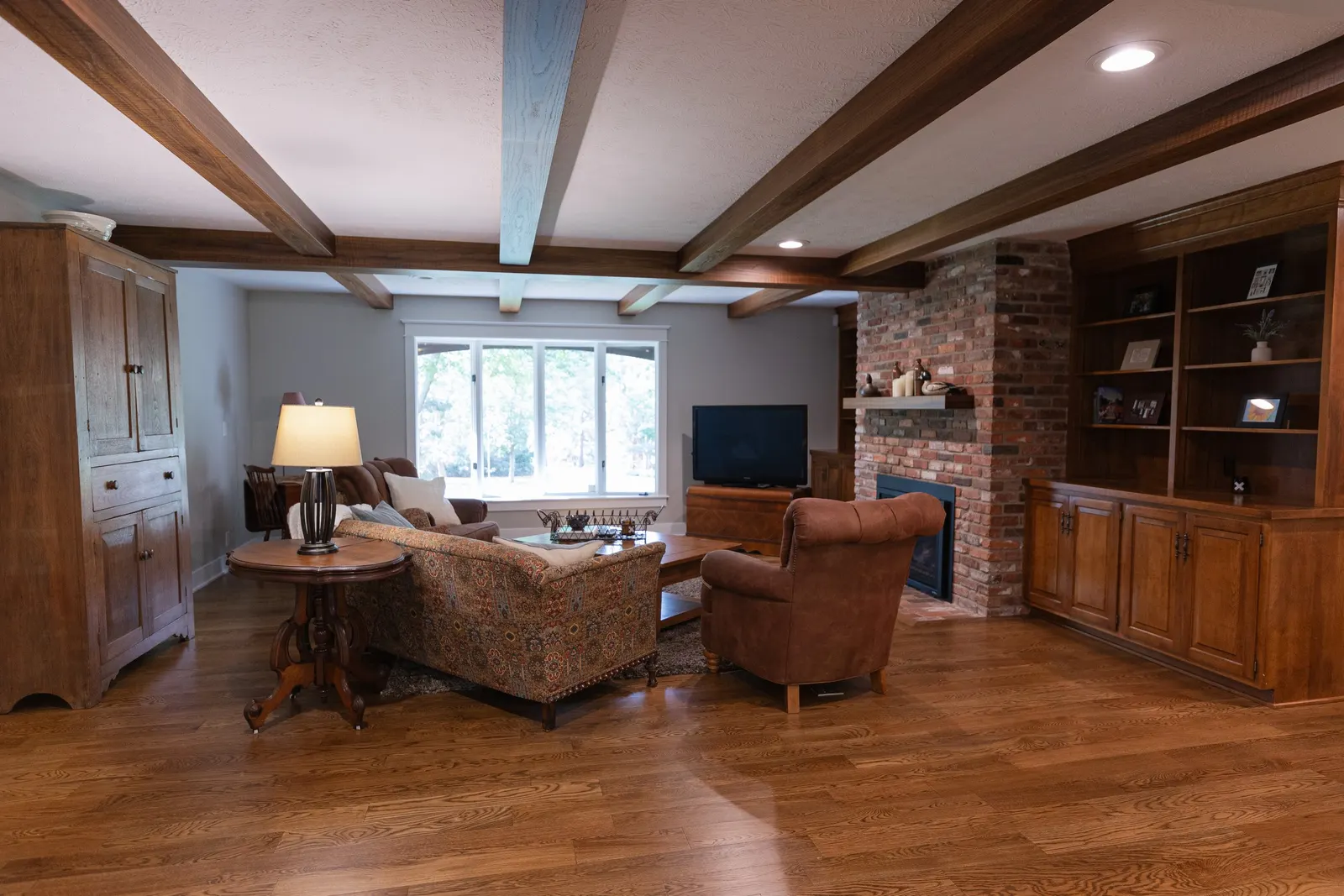 1974 Living Room Remodel, whole home remodel, wood floors, craftsmanship, farmhouse style, large windows, custom wood beams, brick fireplace, wood built-ins, can lighting, dark wood, craftsmanship, wood mantel.