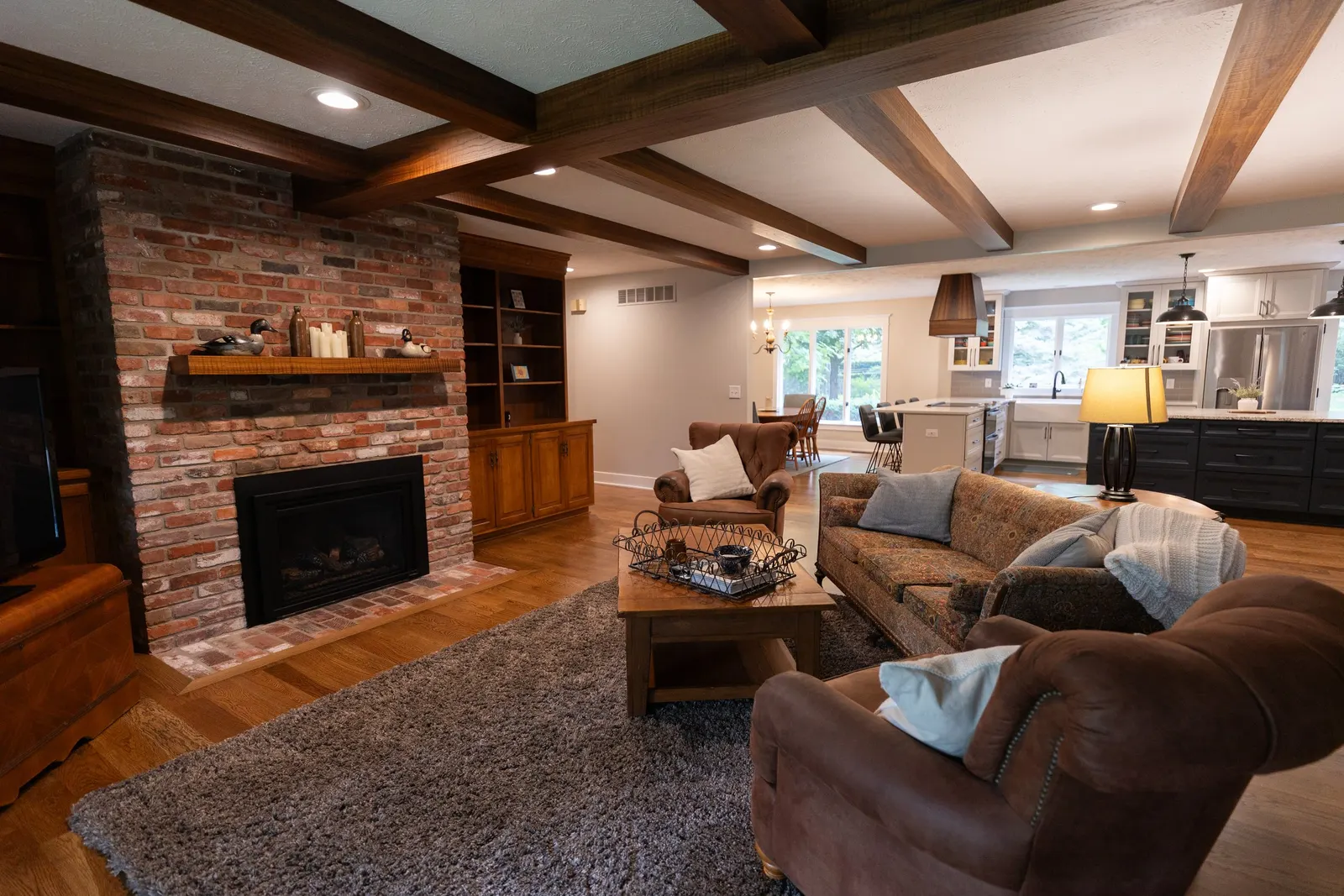 1974 Living Room Remodel, whole home remodel, wood floors, craftsmanship, farmhouse style, large windows, custom wood beams, brick fireplace, wood built-ins, can lighting, dark wood, craftsmanship, wood mantel.