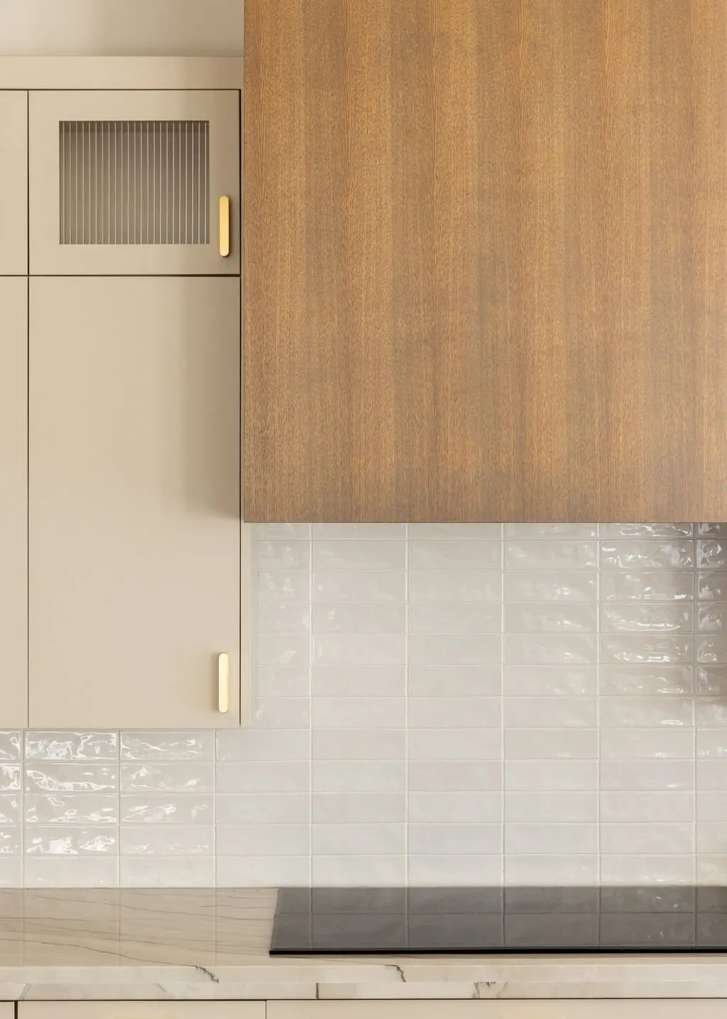Kitchen countertop with beige cabinetry, wooden surface, and white tiled backsplash.