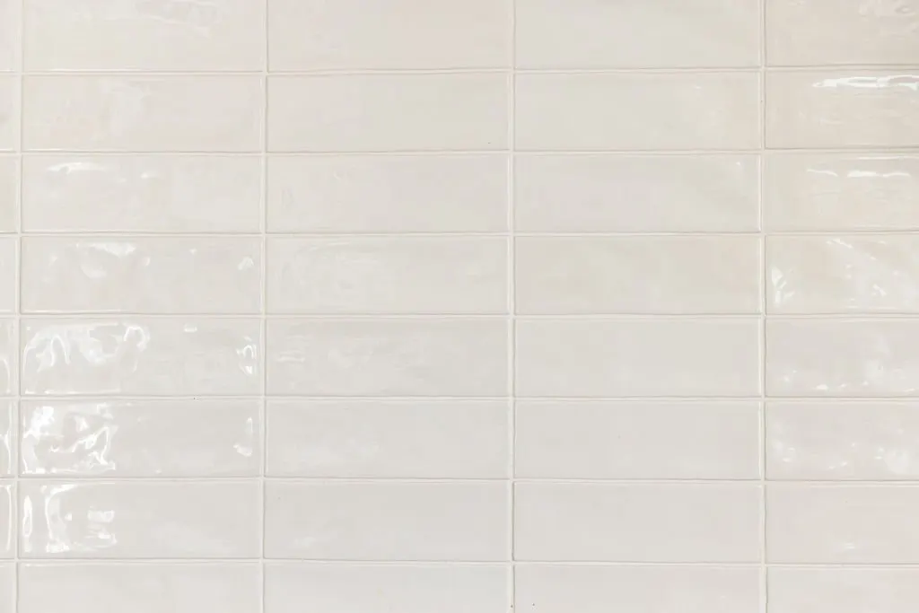 Close-up of a beige tile wall with grout lines.