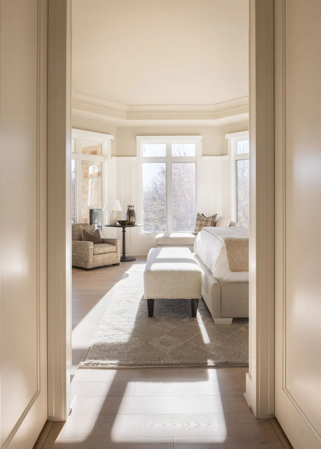 Bright living room with large windows, white walls, beige furniture, and a cozy, inviting atmosphere.
