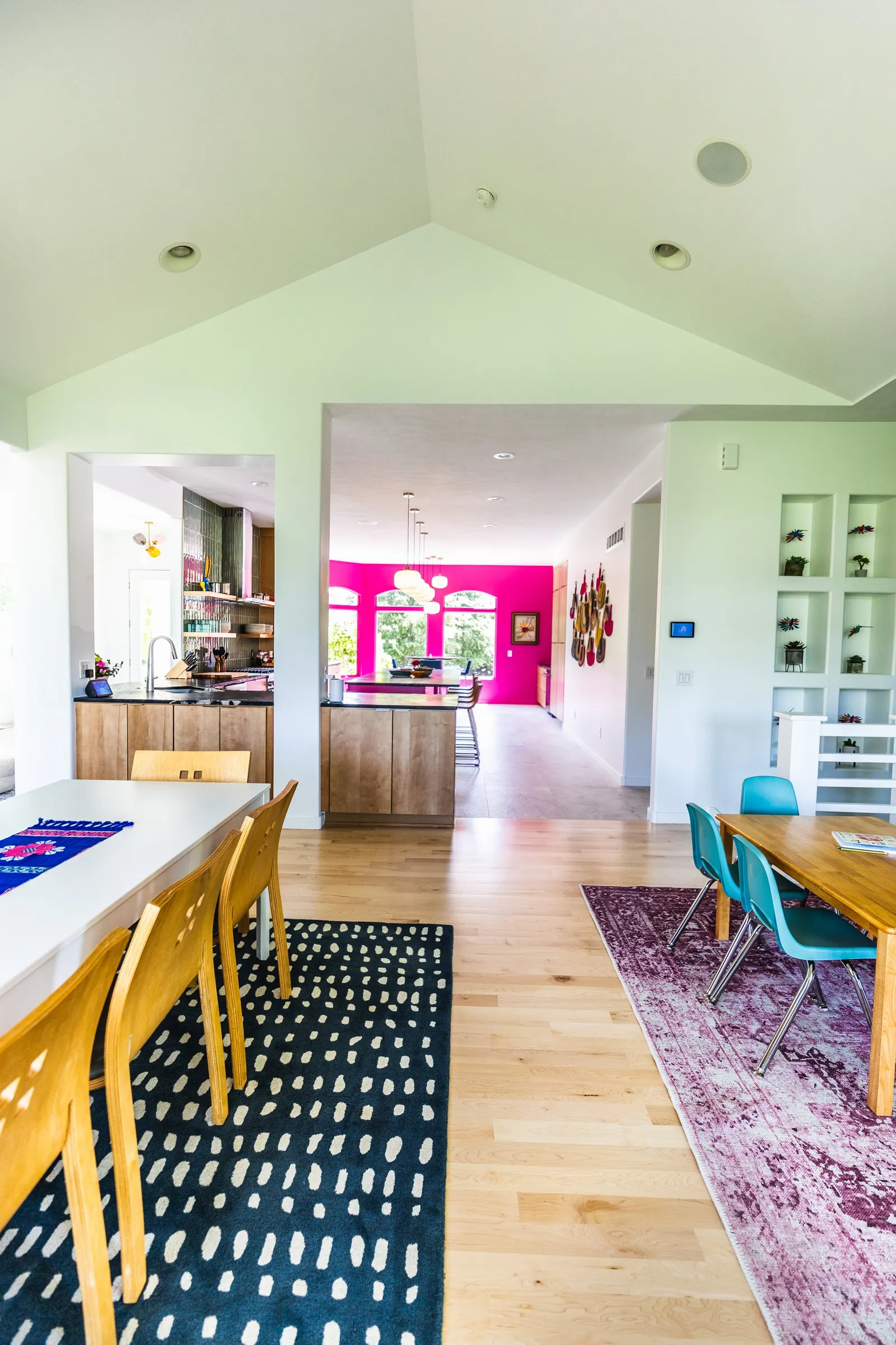 Open-concept dining and kitchen area with colorful decor, wooden furniture, and bright walls.