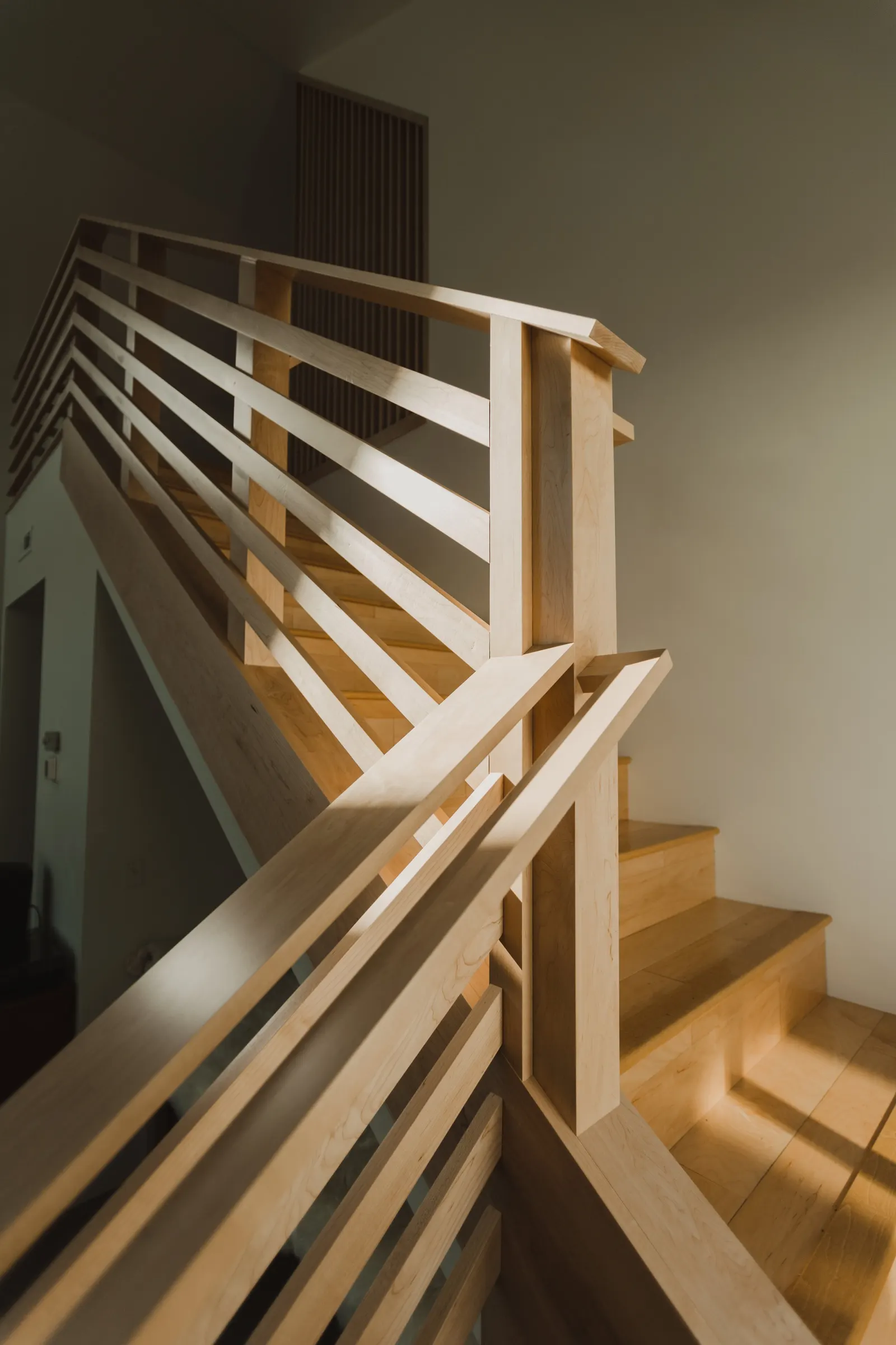 Wooden staircase with horizontal railing balusters and steps in a well-lit residential interior.
