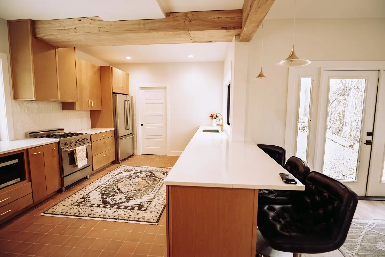 Forest House Kitchen Remodel, Whole Home Remodel, gold hardware, boho chic, farmhouse sink, custom hood, custom wood cabinets, tile floor, stainless steel appliances, white quartz countertops, large windows, wood beams, craftsmanship, brick accents.