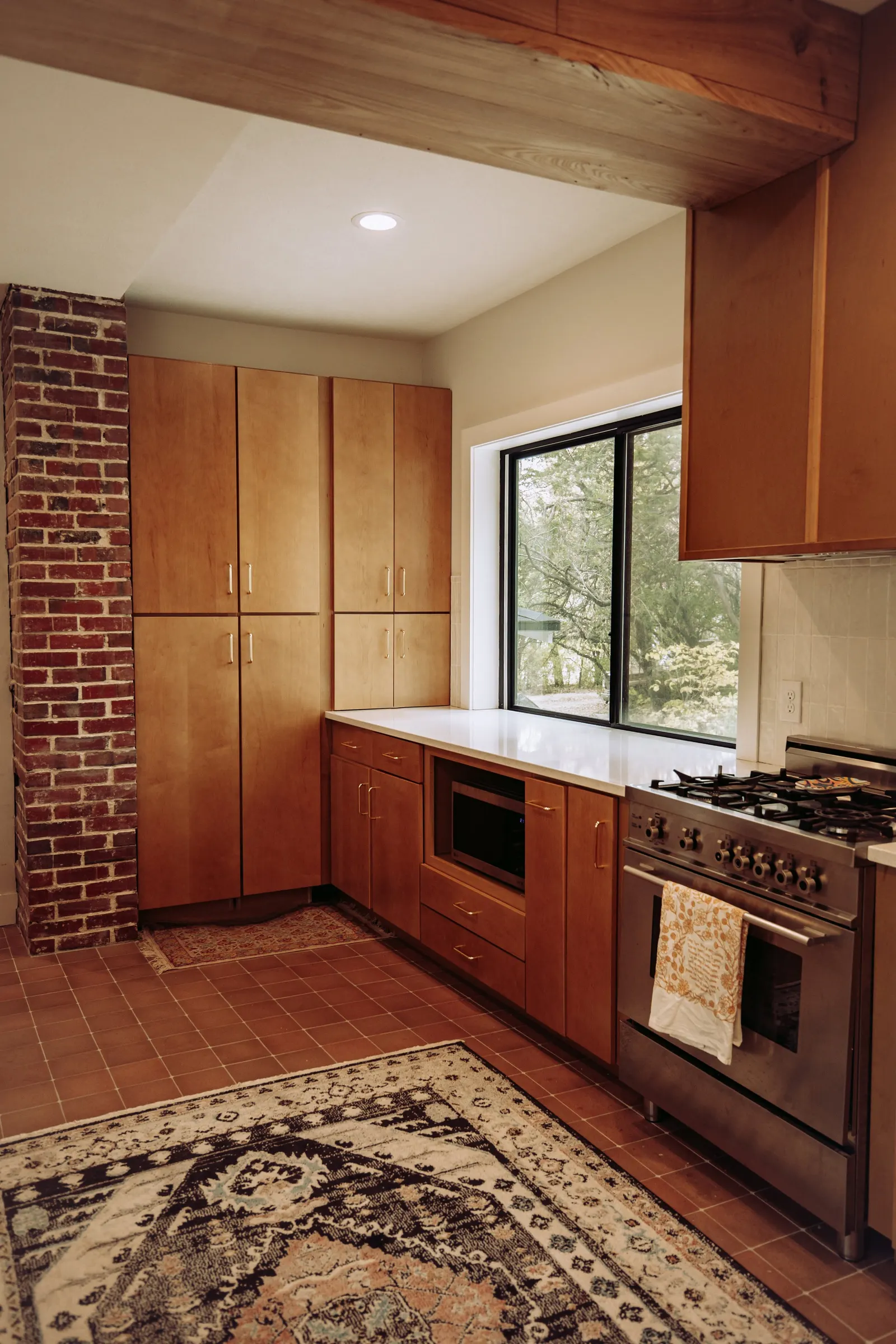 Forest House Kitchen Remodel, Whole Home Remodel, gold hardware, boho chic, farmhouse sink, custom hood, custom wood cabinets, tile floor, stainless steel appliances, white quartz countertops, large windows, wood beams, craftsmanship, brick accents.