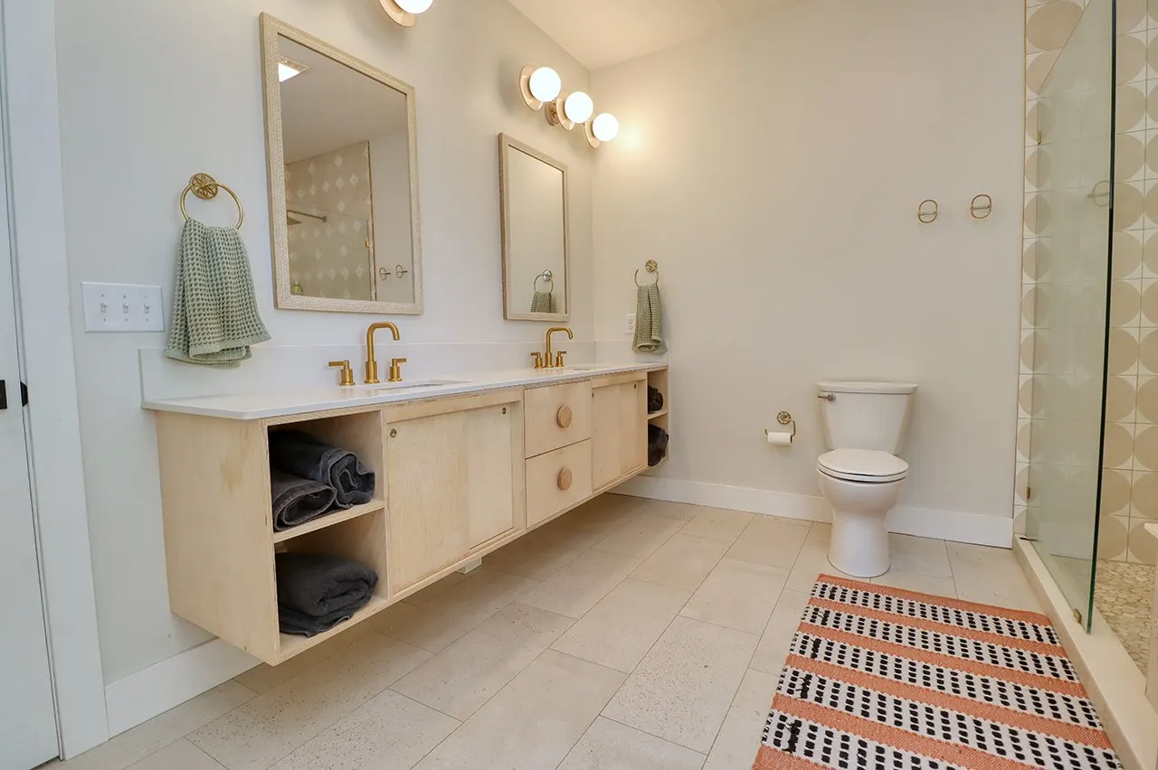 Forest House Remodel, whole home remodel, primary en-suite, free standing bathtub, walk-in shower, tile floor, large windows, mid century modern design, wood vanity, white quartz countertops, brass fixtures, custom vanity.