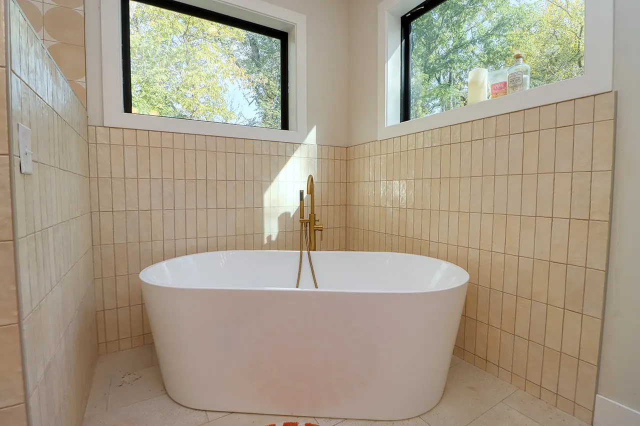 Forest House Remodel, whole home remodel, primary en-suite, free standing bathtub, walk-in shower, tile floor, large windows, mid century modern design, wood vanity, white quartz countertops, brass fixtures, custom vanity.
