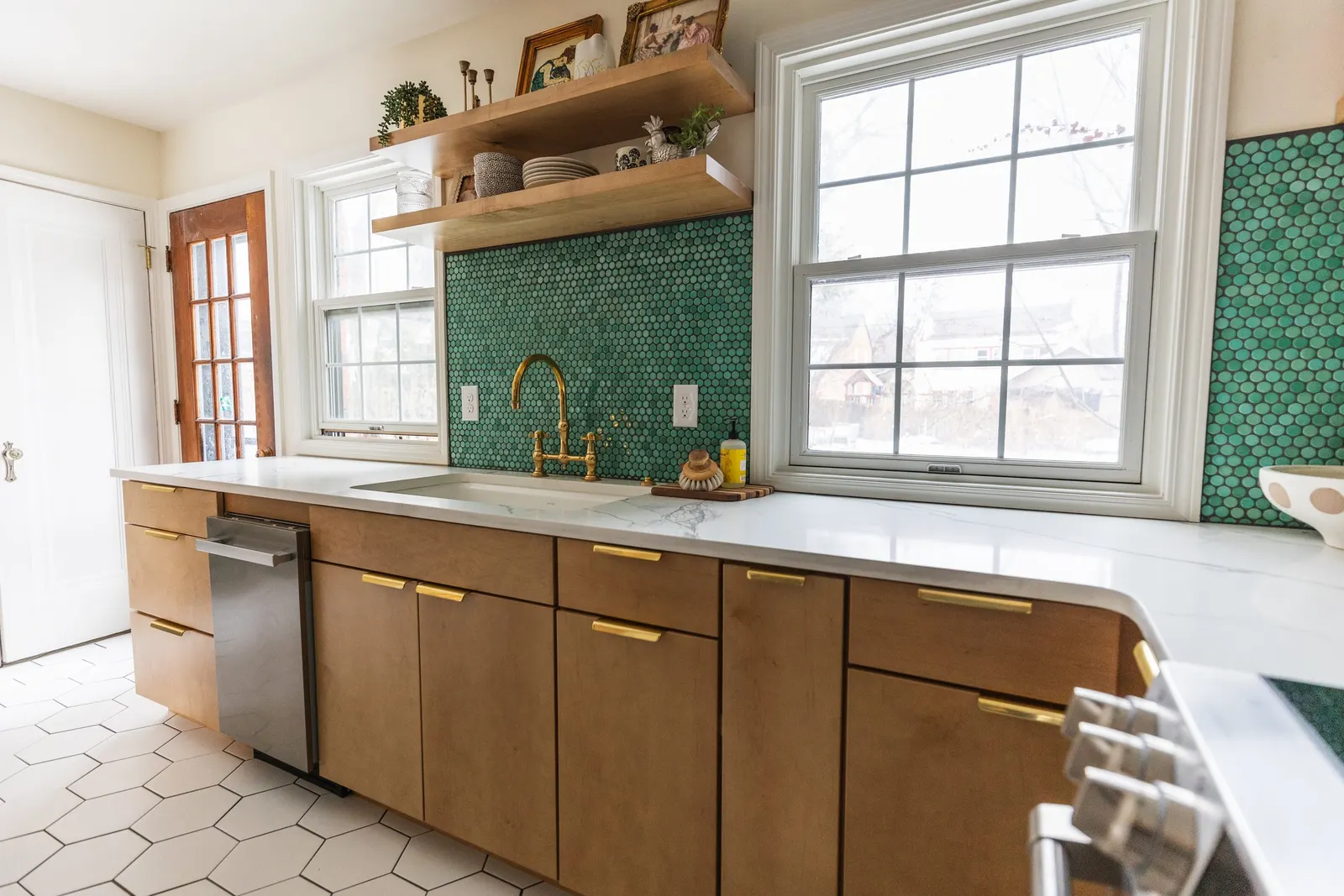Kitchen with wooden cabinets, a white countertop, green penny tile backsplash, and two large windows providing natural light. Kitchen Remodel in Lincoln, Nebraska.