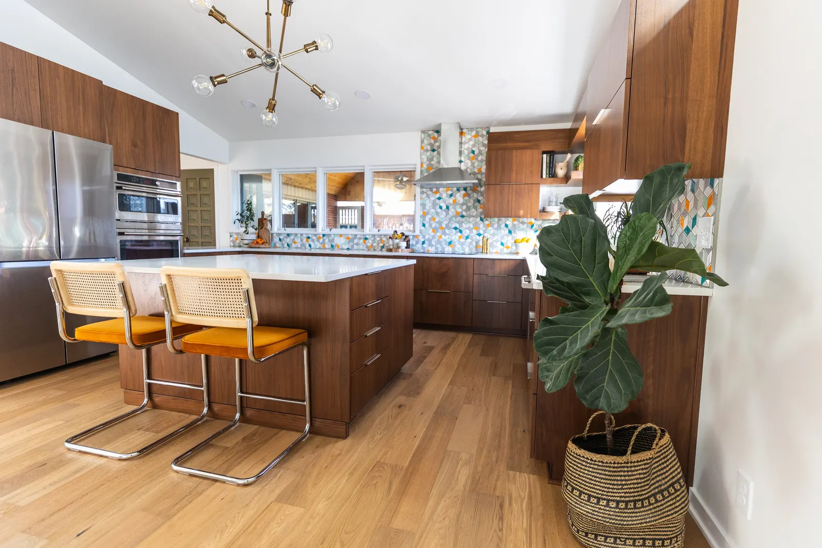 A modern mid-century kitchen remodel with wooden cabinets, a white countertop, a colorful unique tile backsplash. Kitchen Remodel in Lincoln, Nebraska.